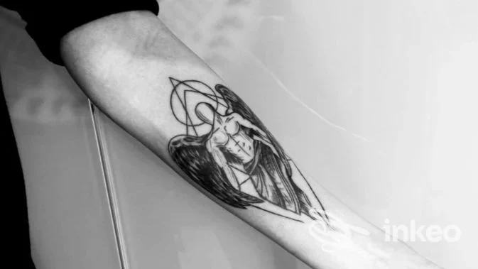 Avambraccio con tatuaggio stilizzato in bianco e nero di figura alata, Tattoo Giovanett, Trento.
