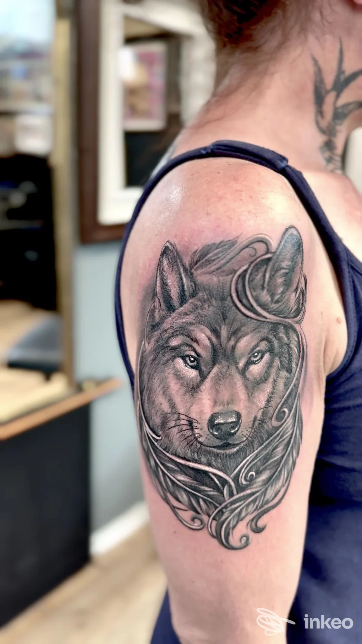 Tatuaggio realistico di testa di lupo in bianco e nero sul braccio superiore, realizzato da Universo tattoo a Rovereto.