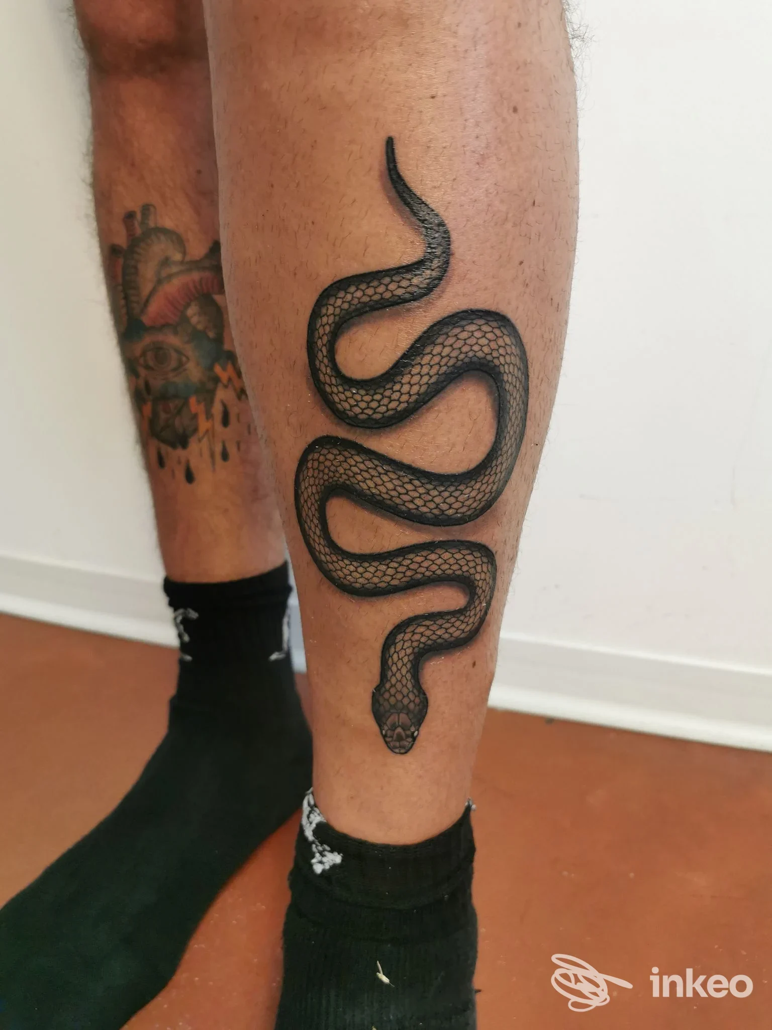 Tatuaggio serpente nero sul polpaccio; foto scattata in studio ART FACTORY TATTOO a Gubbio, dettaglio della gamba e altro tatuaggio sul polpaccio opposto.