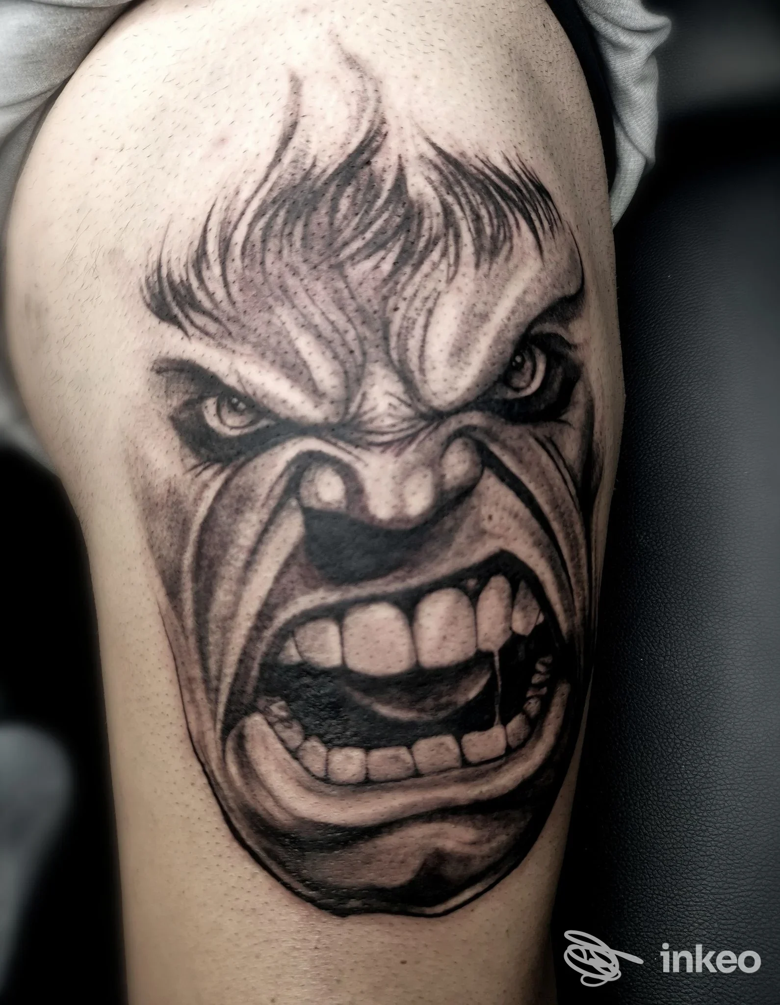 Grande tatuaggio black & grey di un volto furente sul braccio superiore, Atelier Tattoo Studio di Carmine Cerbone a Corciano.