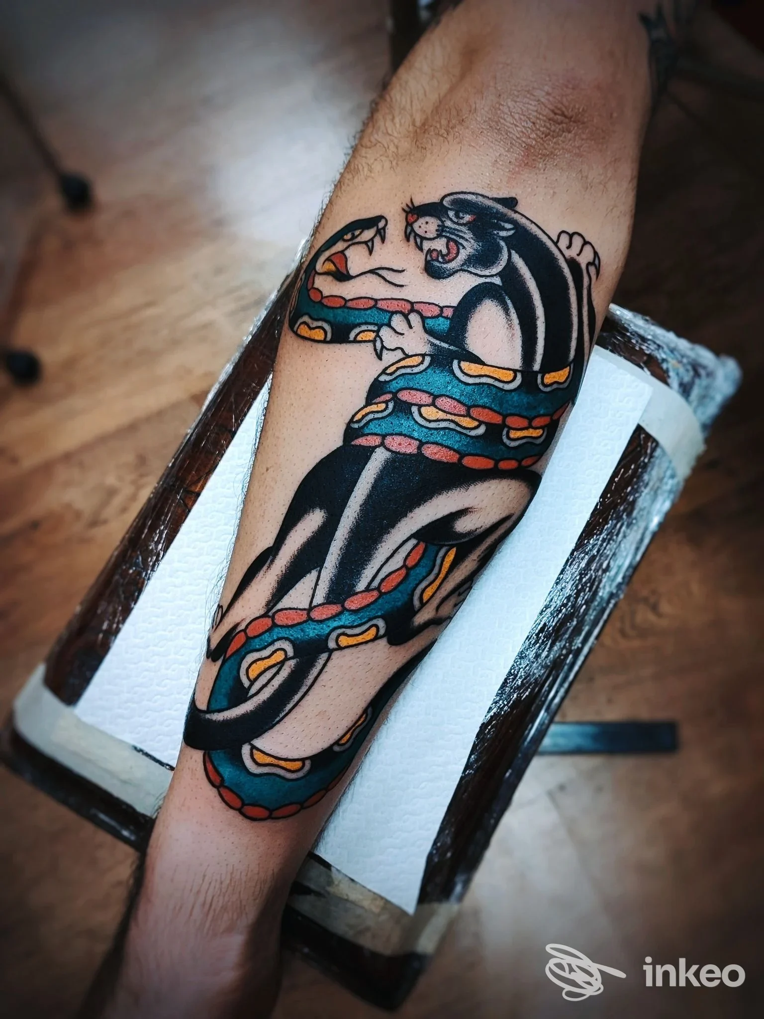 Tatuaggio su avambraccio: pantera nera avvolta da serpente multicolore, foto realizzata da Blue Monkey Tattoo Parlor a Perugia.