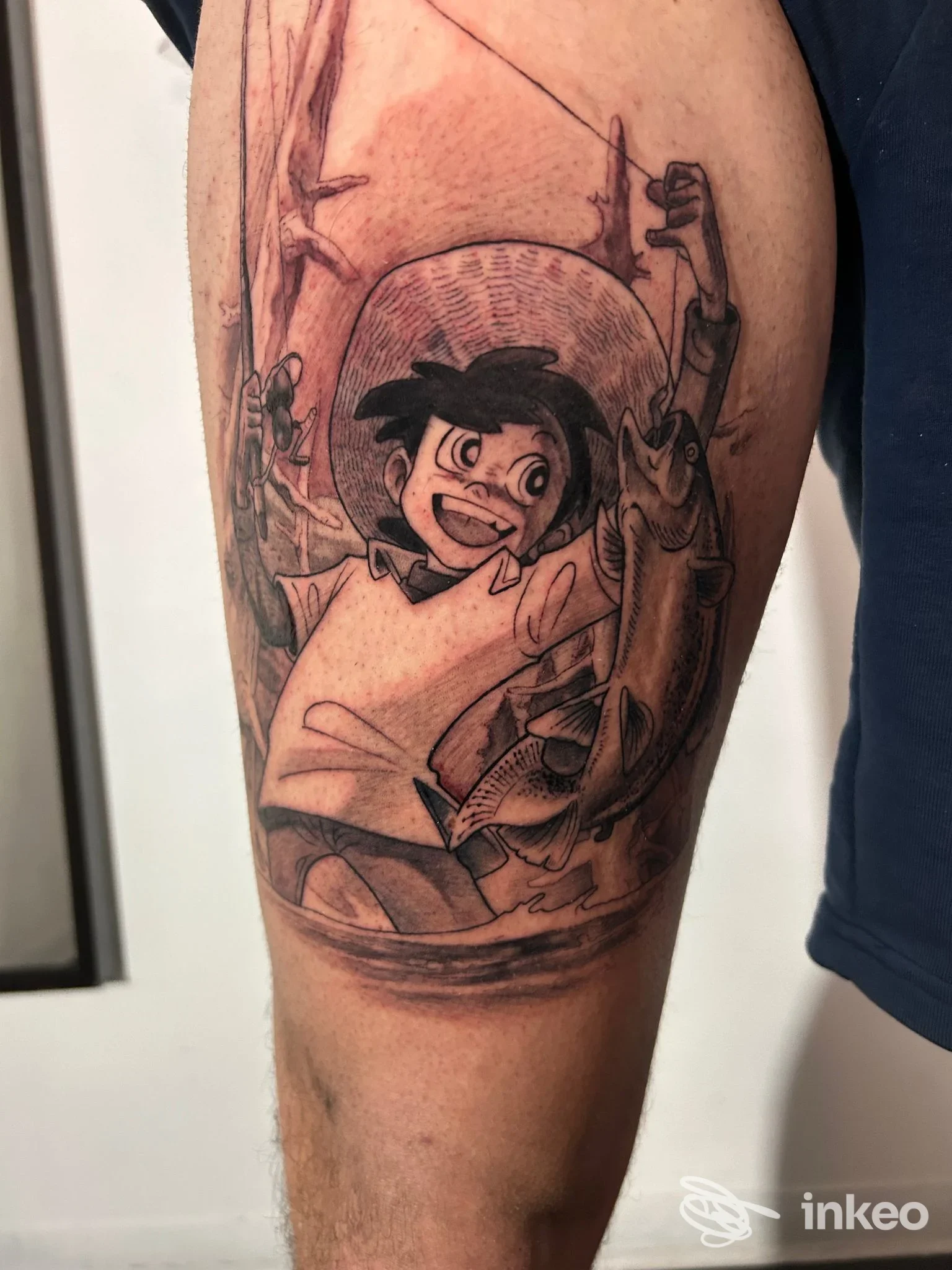 Tatuaggio a inchiostro nero su avambraccio raffigurante un personaggio da cartone che regge due pesci — immagine fornita da Cervone Tattoo Studio, Terni.