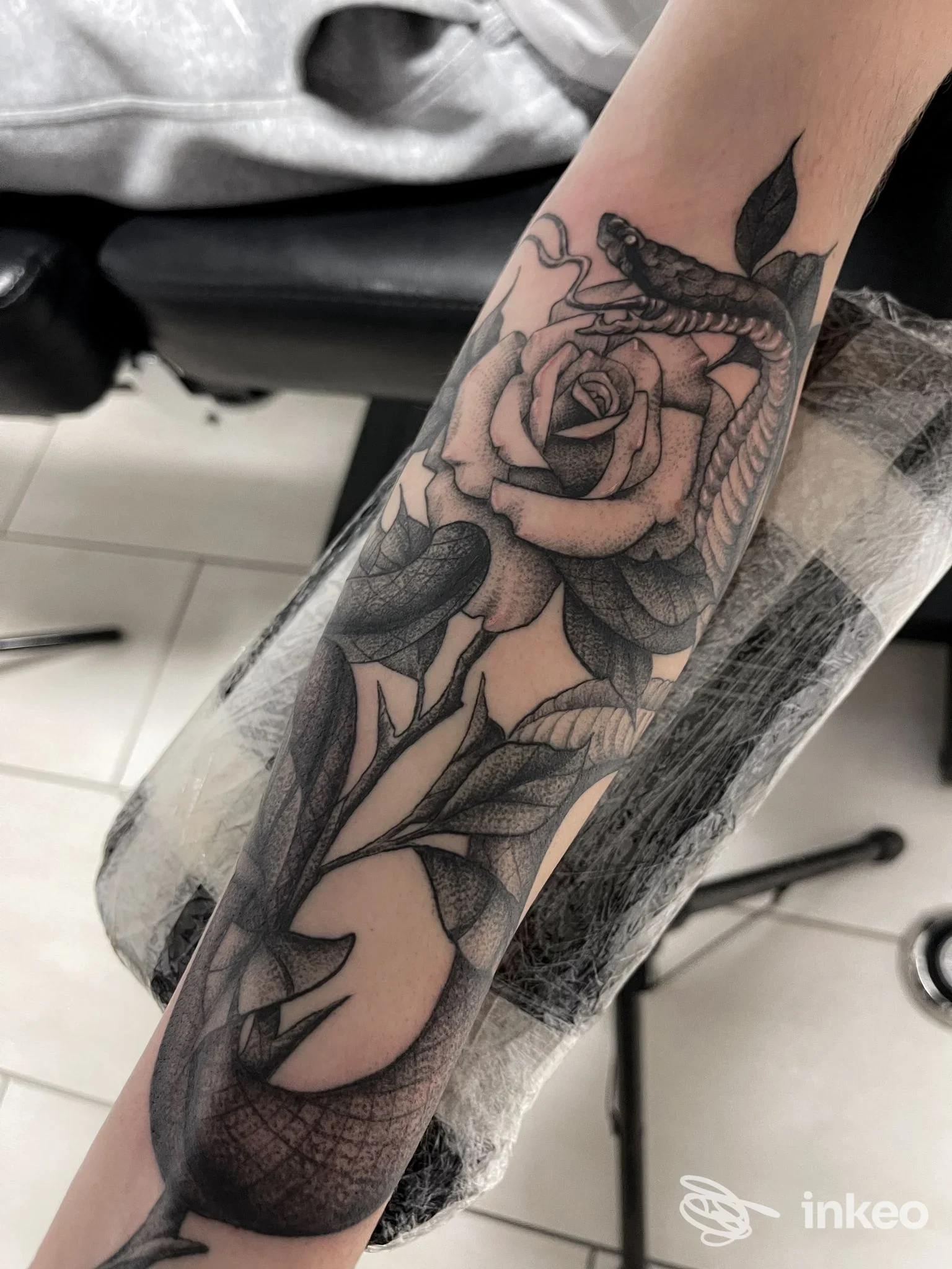 Avambraccio tatuato con rosa e serpente in bianco e nero, lavoro di Blacklagoon tattoo company a Passignano sul Trasimeno.
