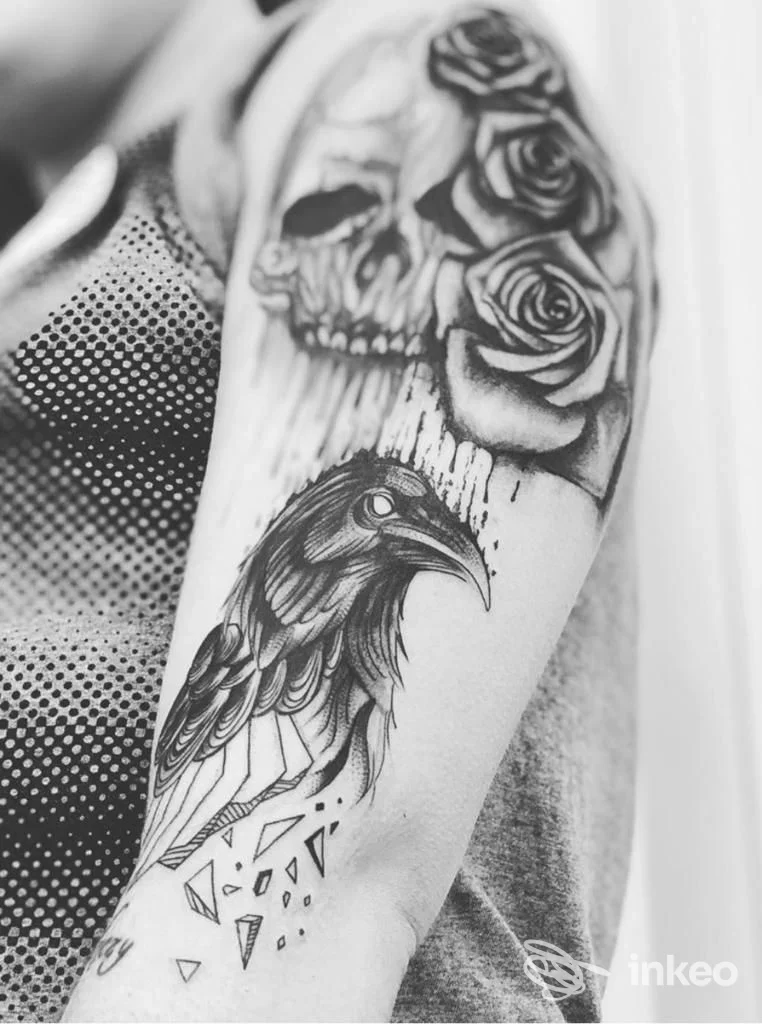 Primo piano di un braccio tatuato con teschio, rose e corvo, immagine fornita da La Tatuaggeria di Ambra Francia a Terni.
