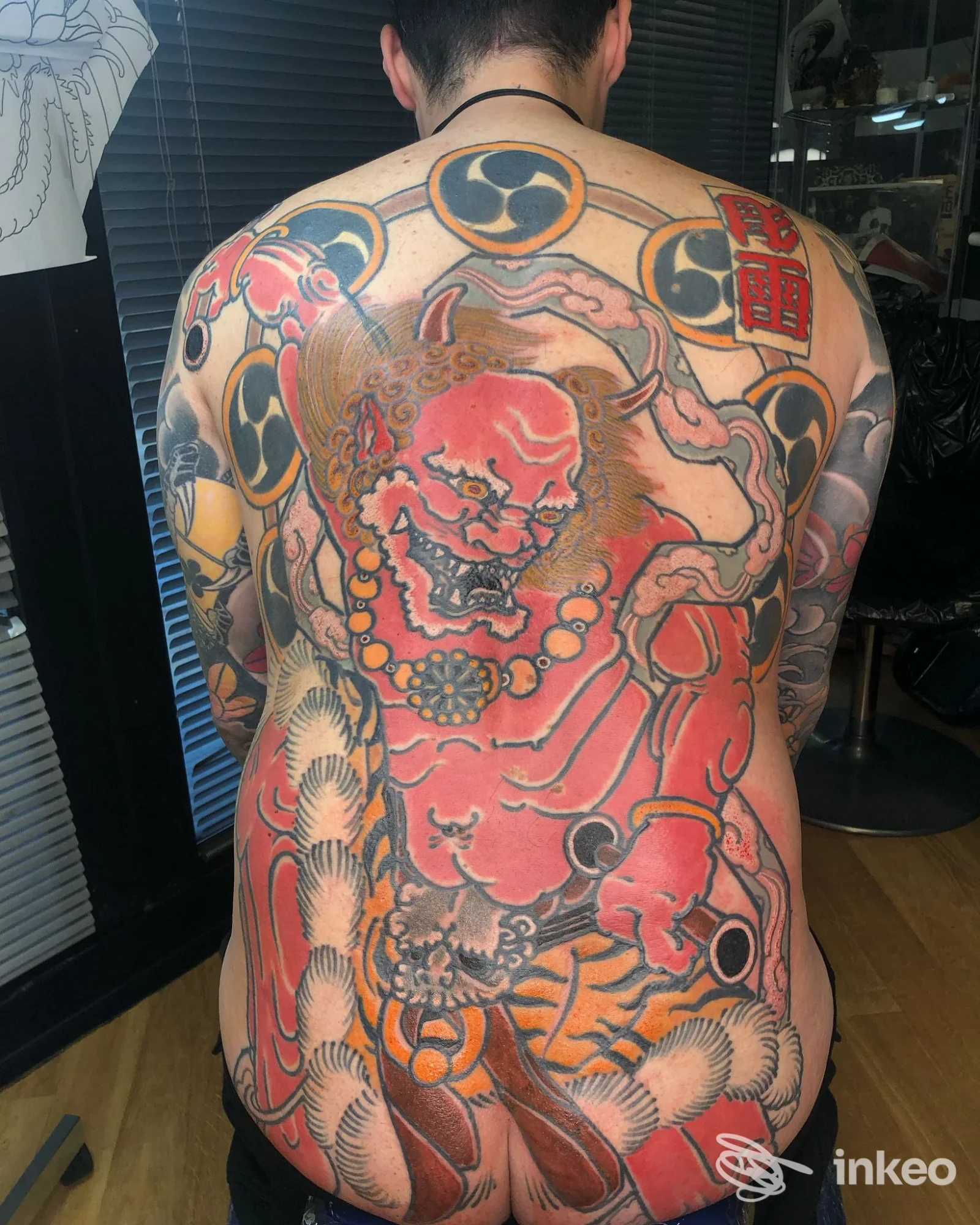 Grande backpiece tradizionale mostrato su schiena reale nel Led Tattoo di Perugia, figura mitologica rossa e motivi ornamentali.