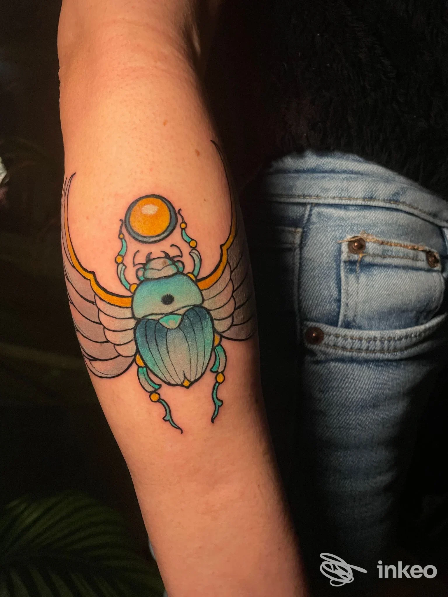 Primo piano di un tatuaggio scarabeo colorato sull'avambraccio, fotografato nello studio Libe Tattoo Studio a Perugia.