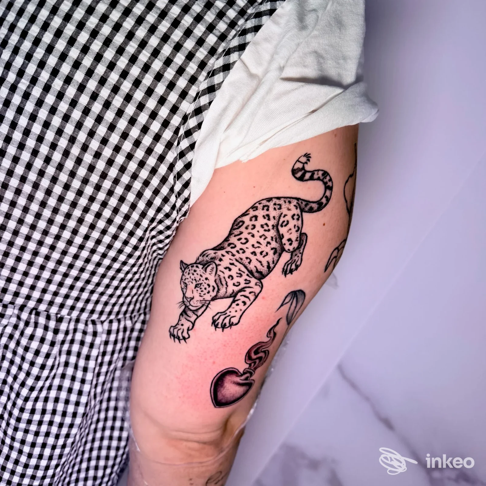 Braccio con tatuaggi visibili, tra cui un giaguaro e un cuore stilizzato; foto per Fraffry Tattoo e Piercing, Amelia.