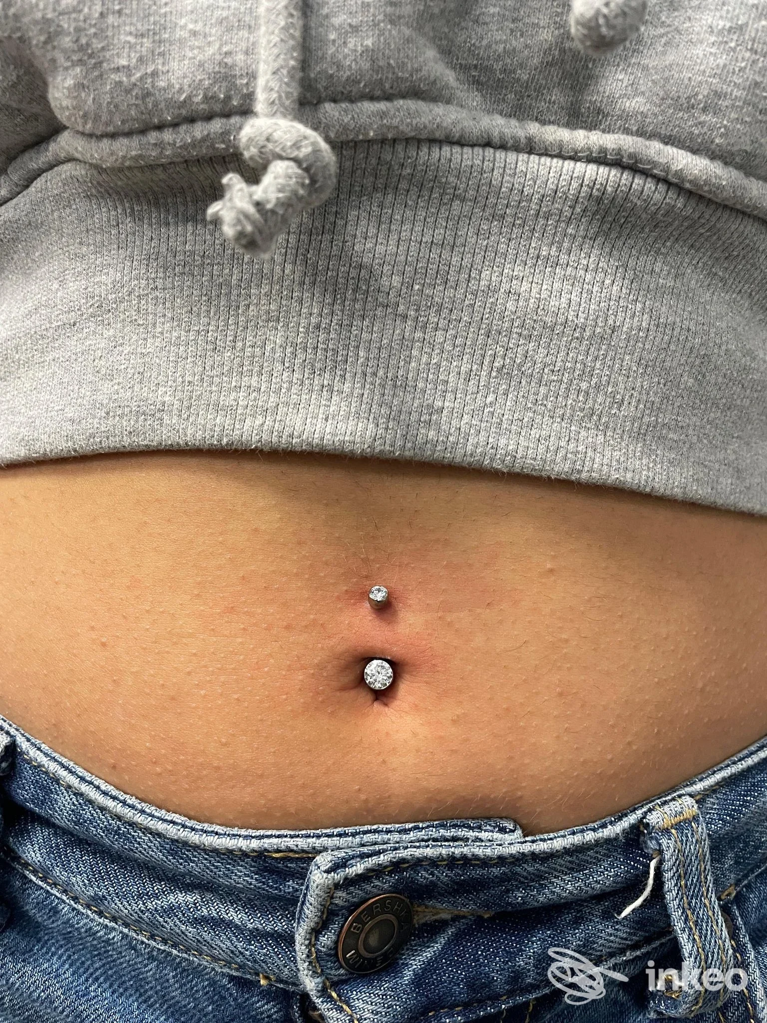 Piercing ombelicale con due gioielli brillanti, foto dello studio MOSCABIANCA tattoostudio a Bastia Umbra, inquadratura del ventre.