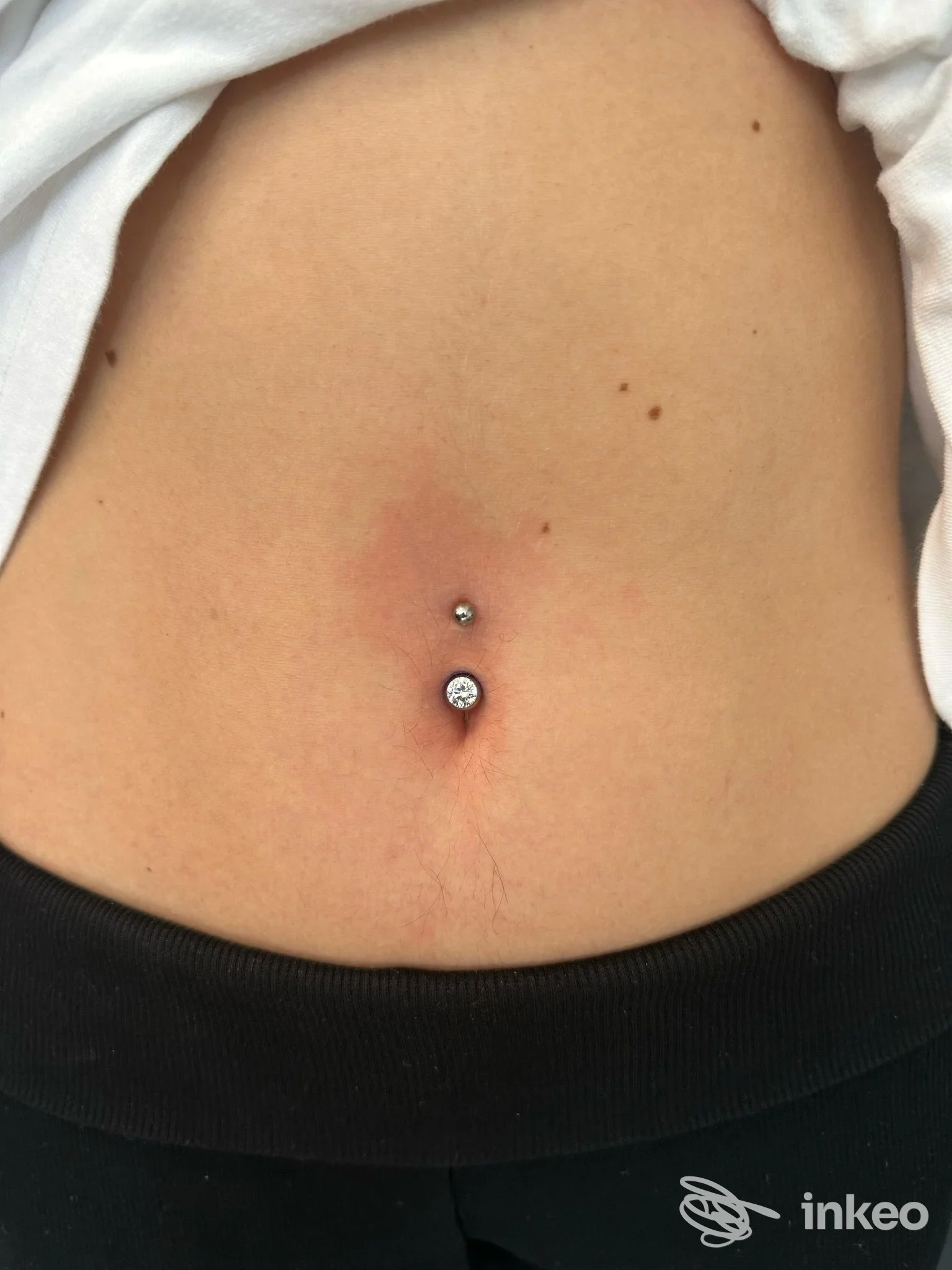 Piercing all'ombelico con due gioielli brillanti, fotografia dello studio MOSCABIANCA tattoostudio a Bastia Umbra.