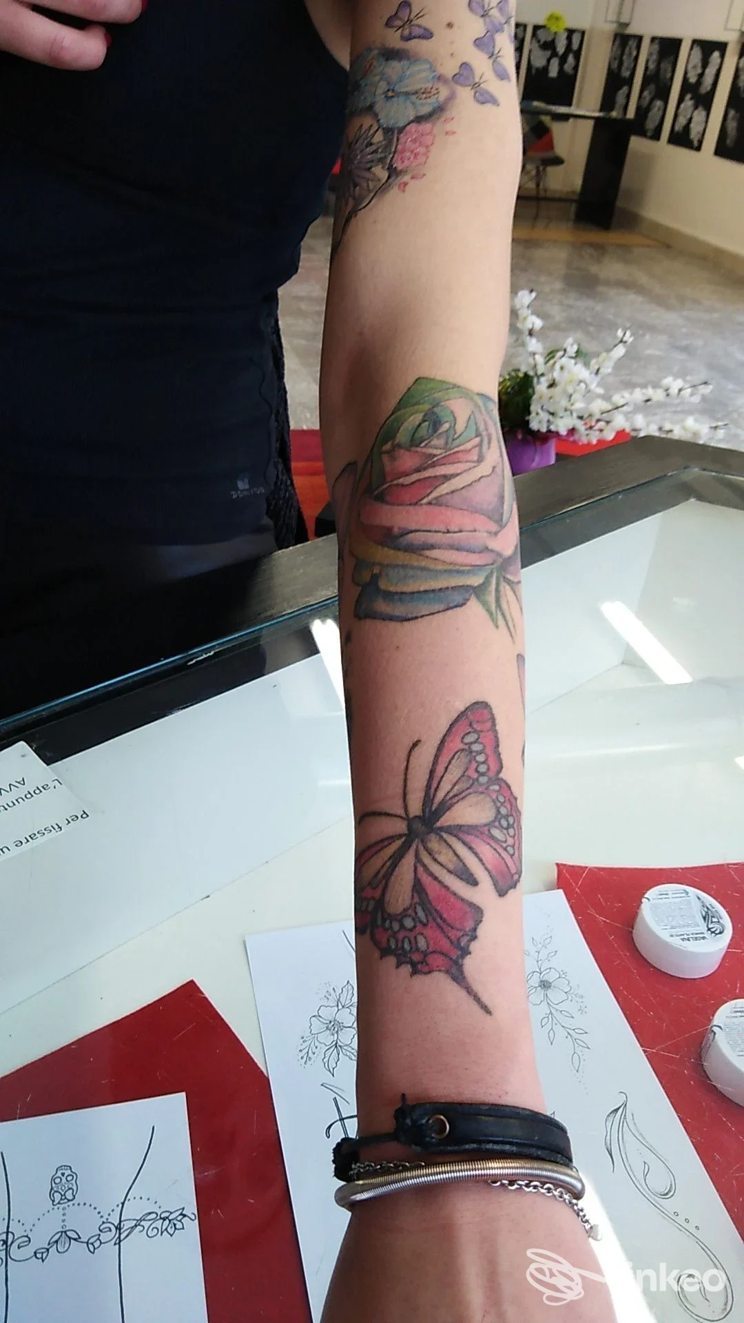 Avambraccio tatuato con rosa colorata vicino al gomito e farfalla rosa più in basso, fotografia effettuata presso Miky Tattoo Saloon, Spoleto.