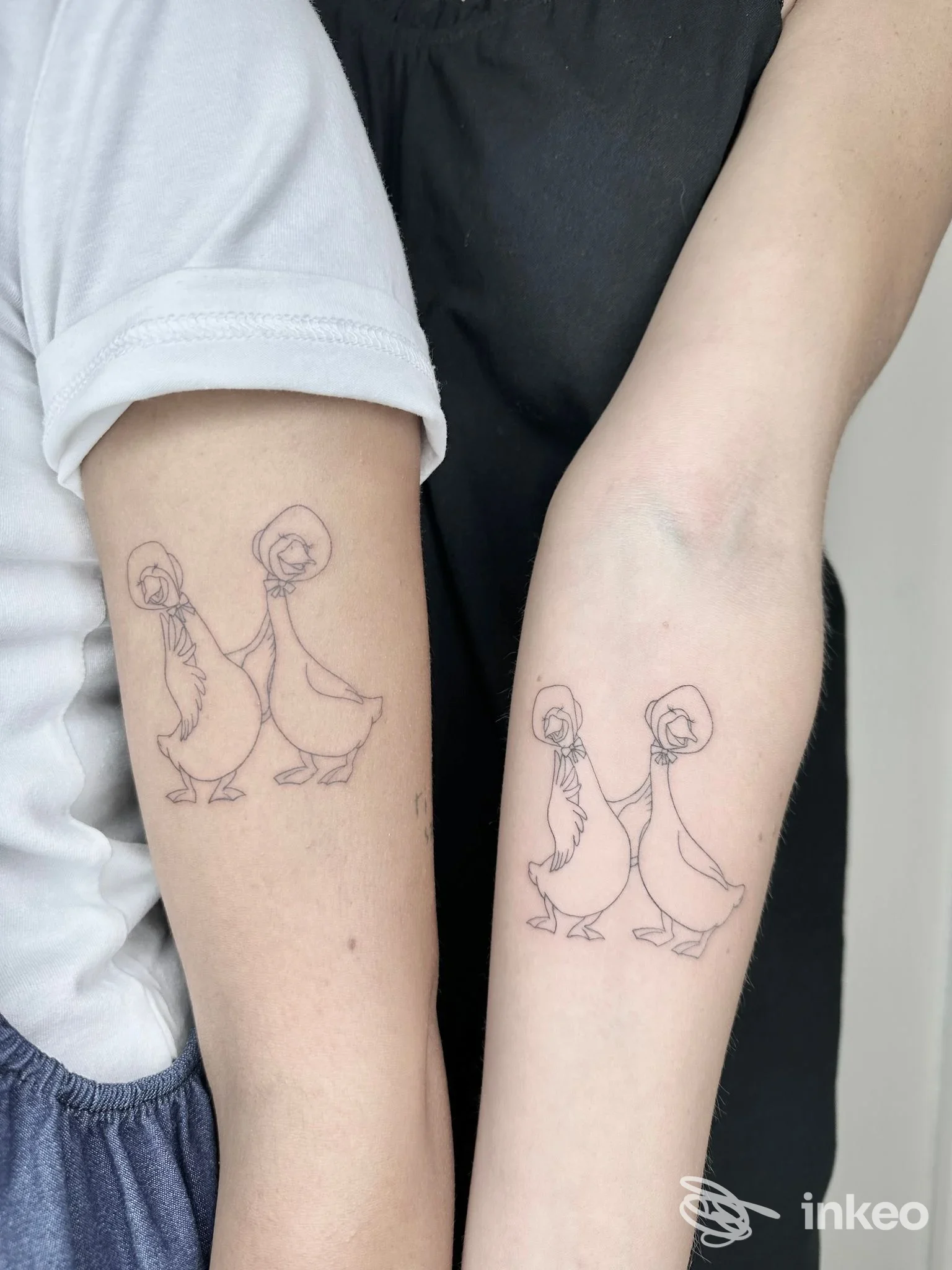 Due avambracci con tatuaggi identici a linee sottili raffiguranti due oche; immagine fornita da NEGOZIO-tattoo studio, Gualdo Tadino.