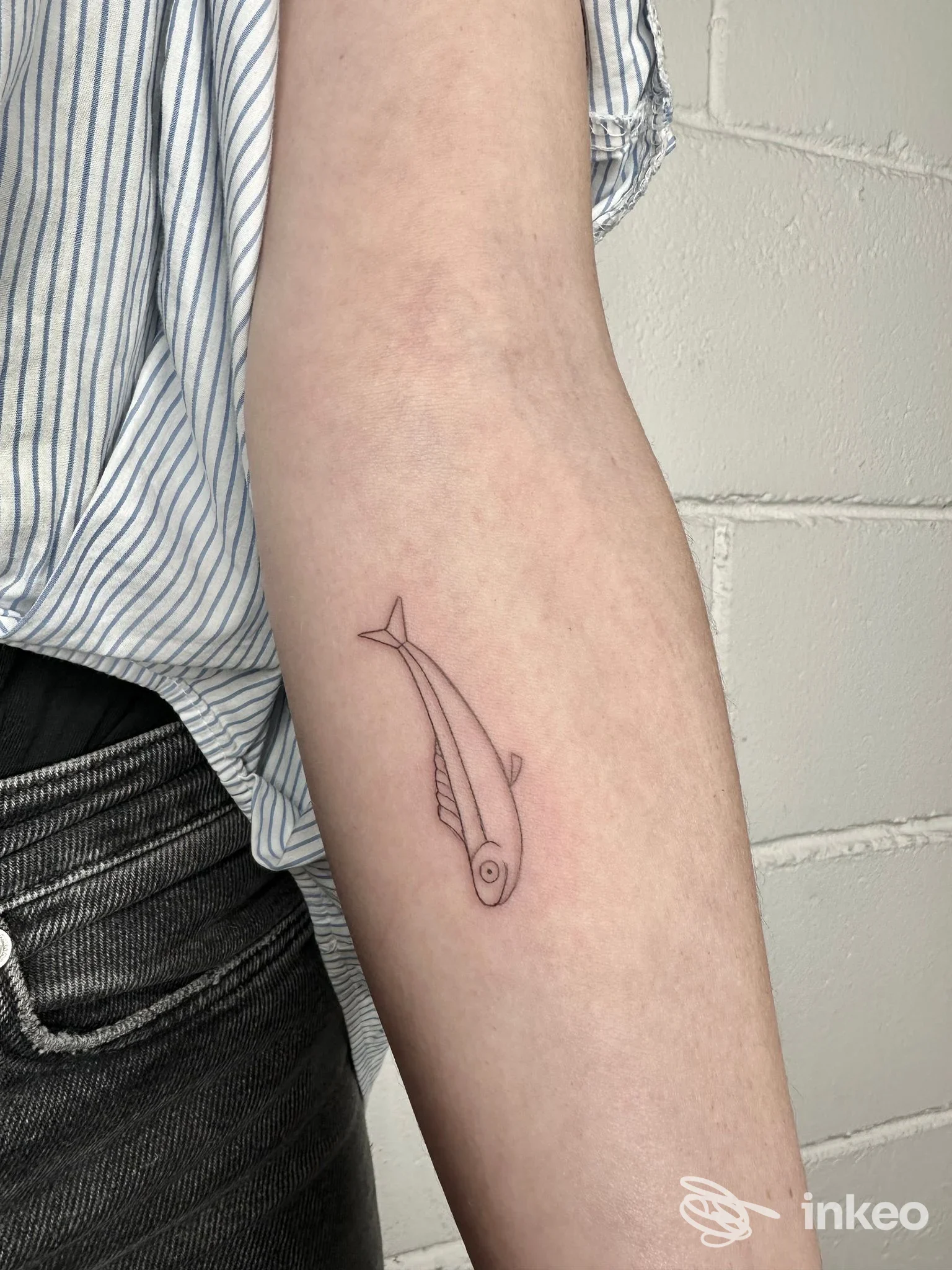 Piccolo tatuaggio lineare a forma di pesce sull'avambraccio interno, NEGOZIO-tattoo studio, Gualdo Tadino.