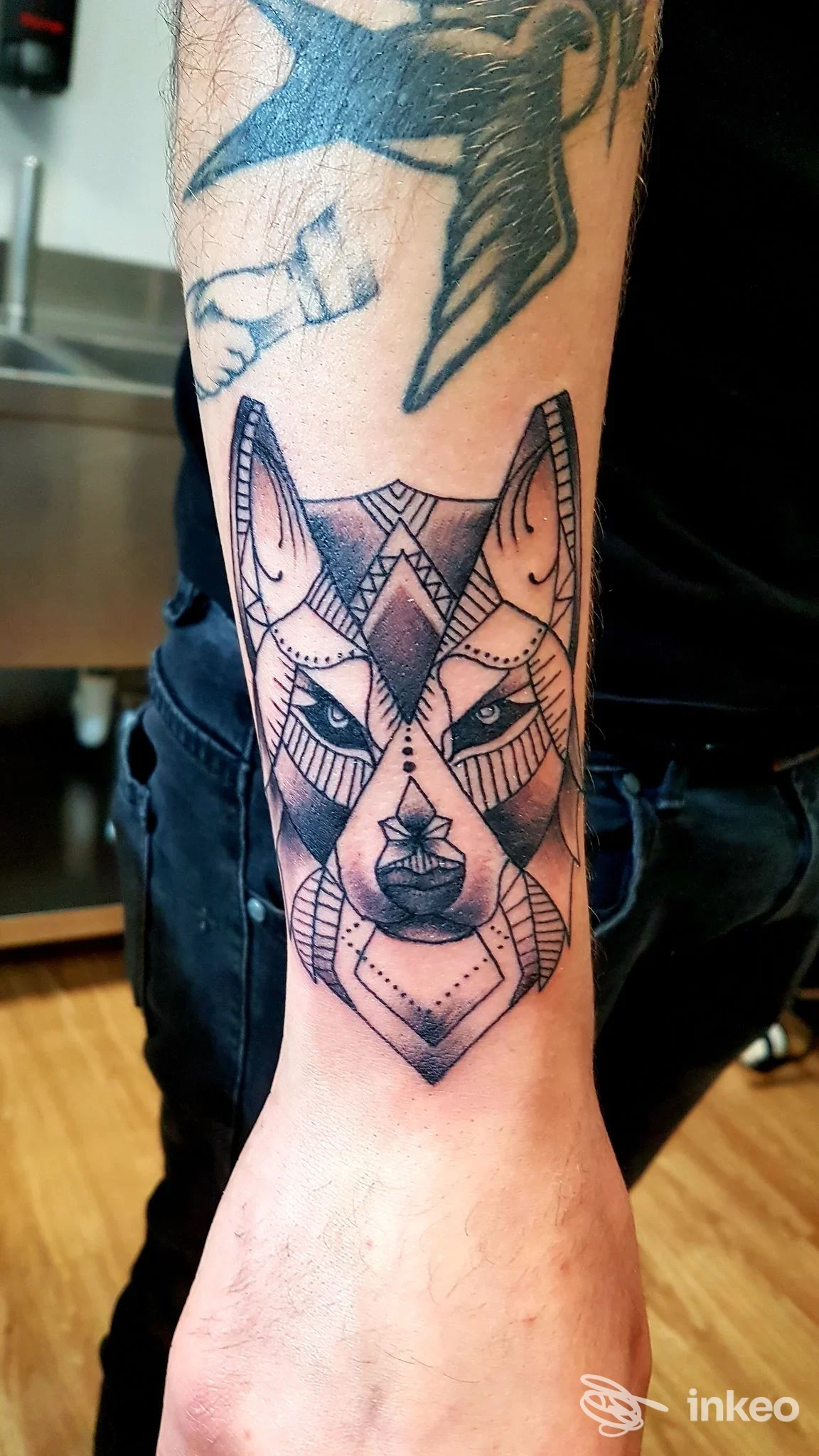 Tatuaggio testa di lupo geometrica in nero sull'avambraccio, foto scattata nello studio Ocean ink tattoo studio a Trevi.