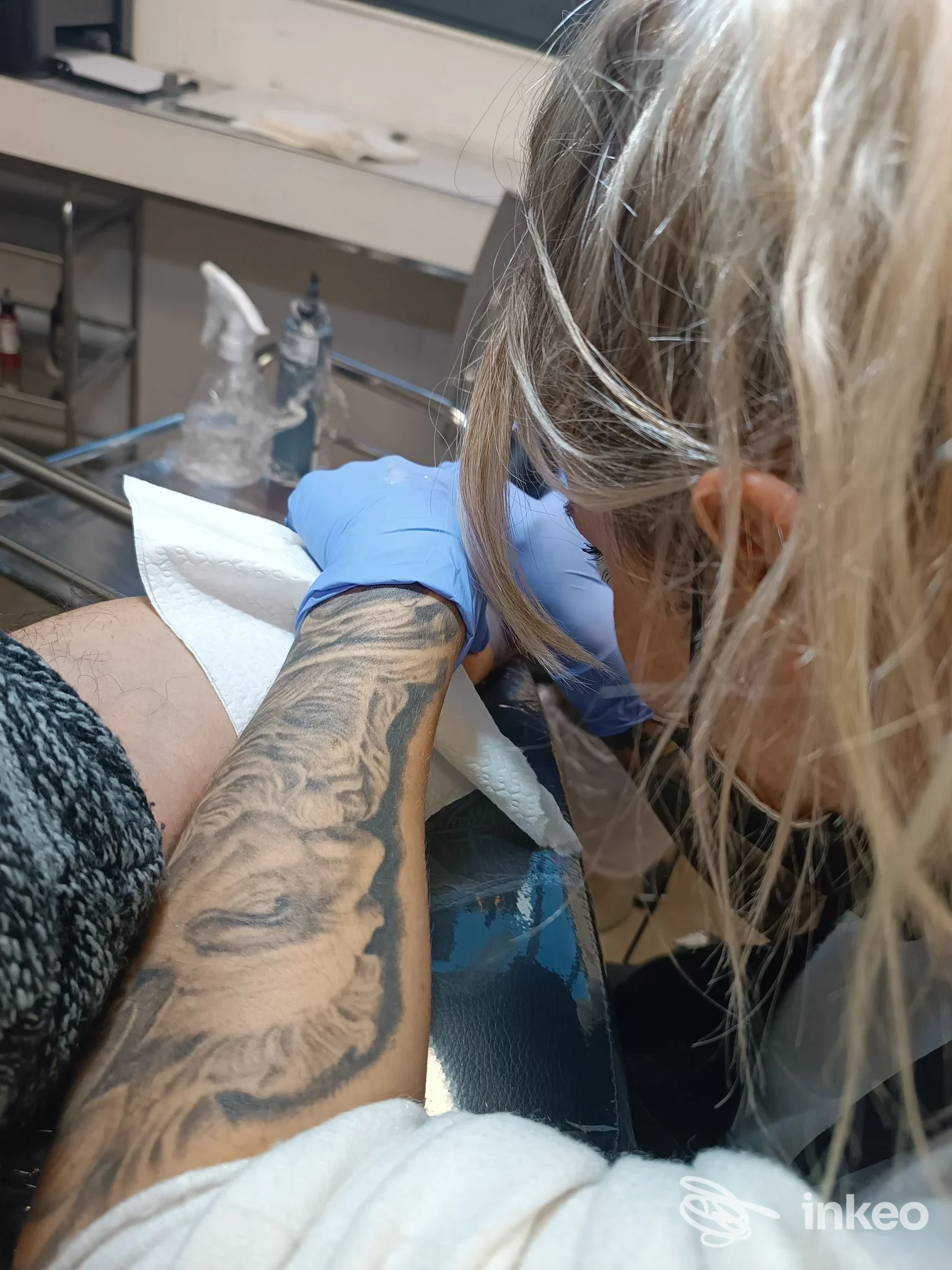 Tatuatrice al lavoro sull'avambraccio di un cliente, tatuaggio in corso nello studio Mamacita Tattoo a Terni.