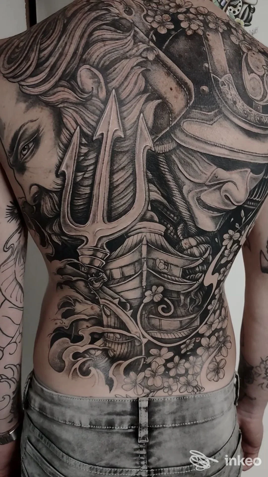 Ampio tatuaggio black & grey che copre l'intera schiena con tridente, elmo guerriero e figure; Martius Tattoo Studio, Cerbara.