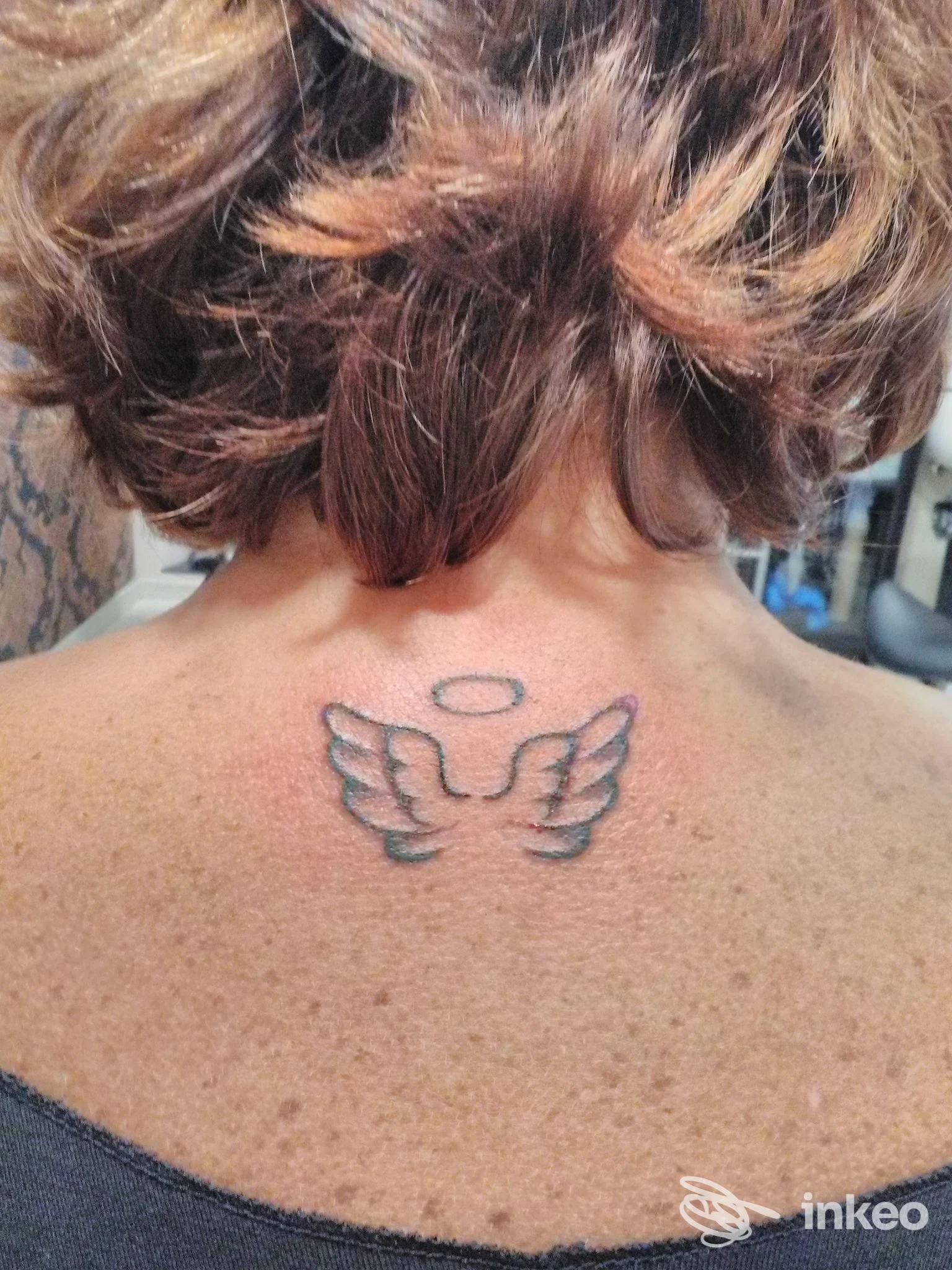 Piccolo tatuaggio con ali e alone sulla parte alta della schiena/collo, realizzato da NIKEDA TATTOO STUDIO, Foligno.