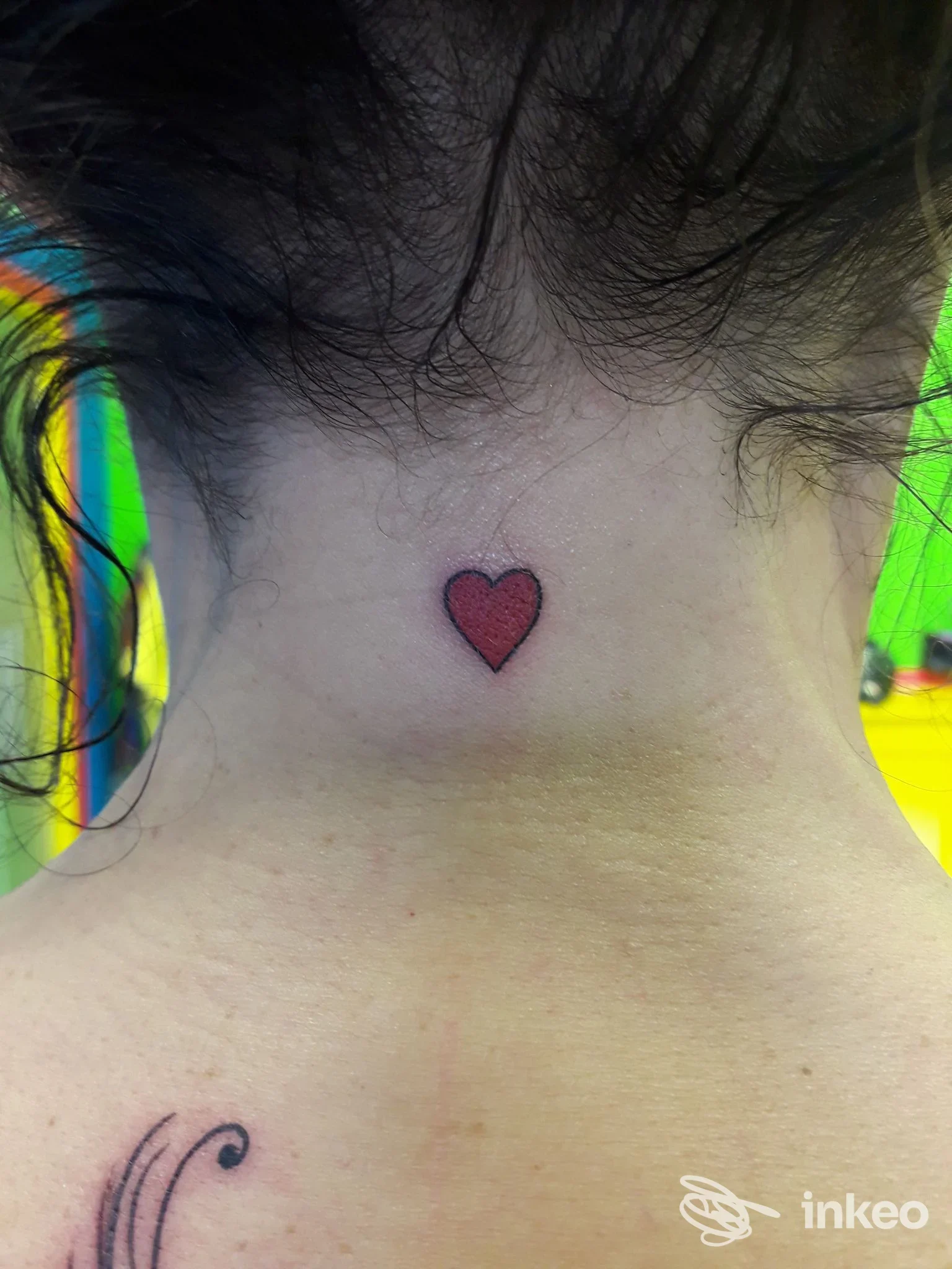 Piccolo cuore tatuato rosso con contorno nero sulla nuca di una persona, foto inviata da Pretty Tattoo di Rossi Sonia, Gubbio.