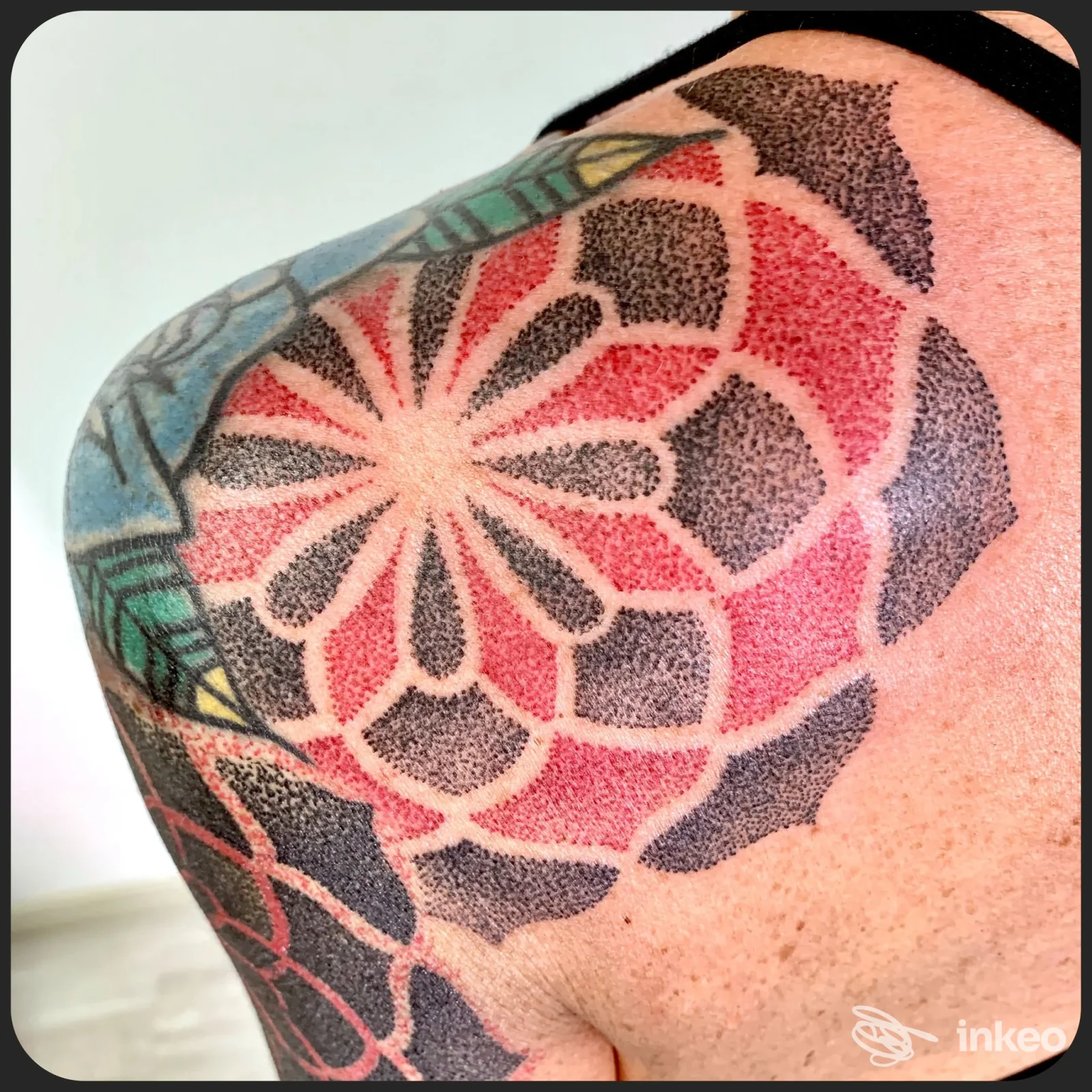Primo piano di un tatuaggio geometrico a puntinato e pieni rossi sulla spalla. Foto per Punto...Tattoo di Francesco Fiorini, Terni.