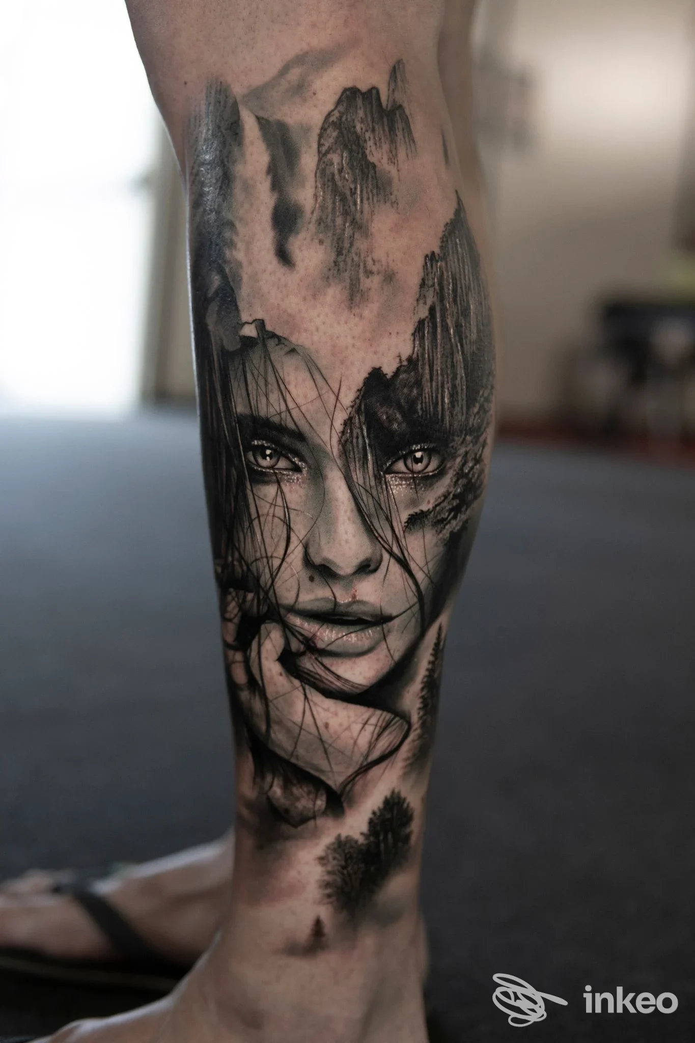 Tatuaggio realistico in bianco e nero su polpaccio con ritratto femminile e paesaggi, Sinkronia Tattoo Studio, Foligno.