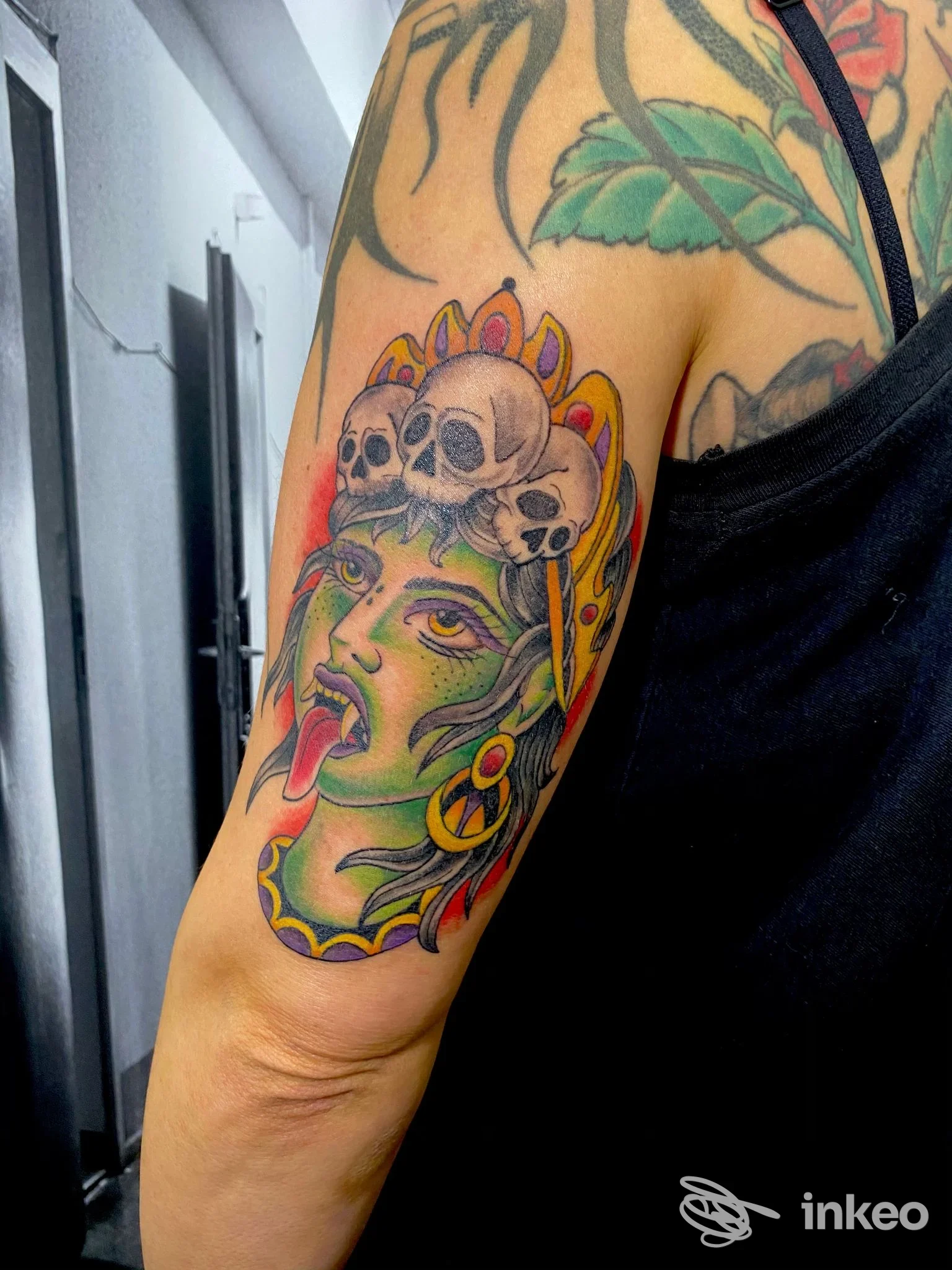 Tatuaggio a colori su braccio superiore: volto stilizzato con teschi, foto fornita da The Prison Tattoo, Gubbio.