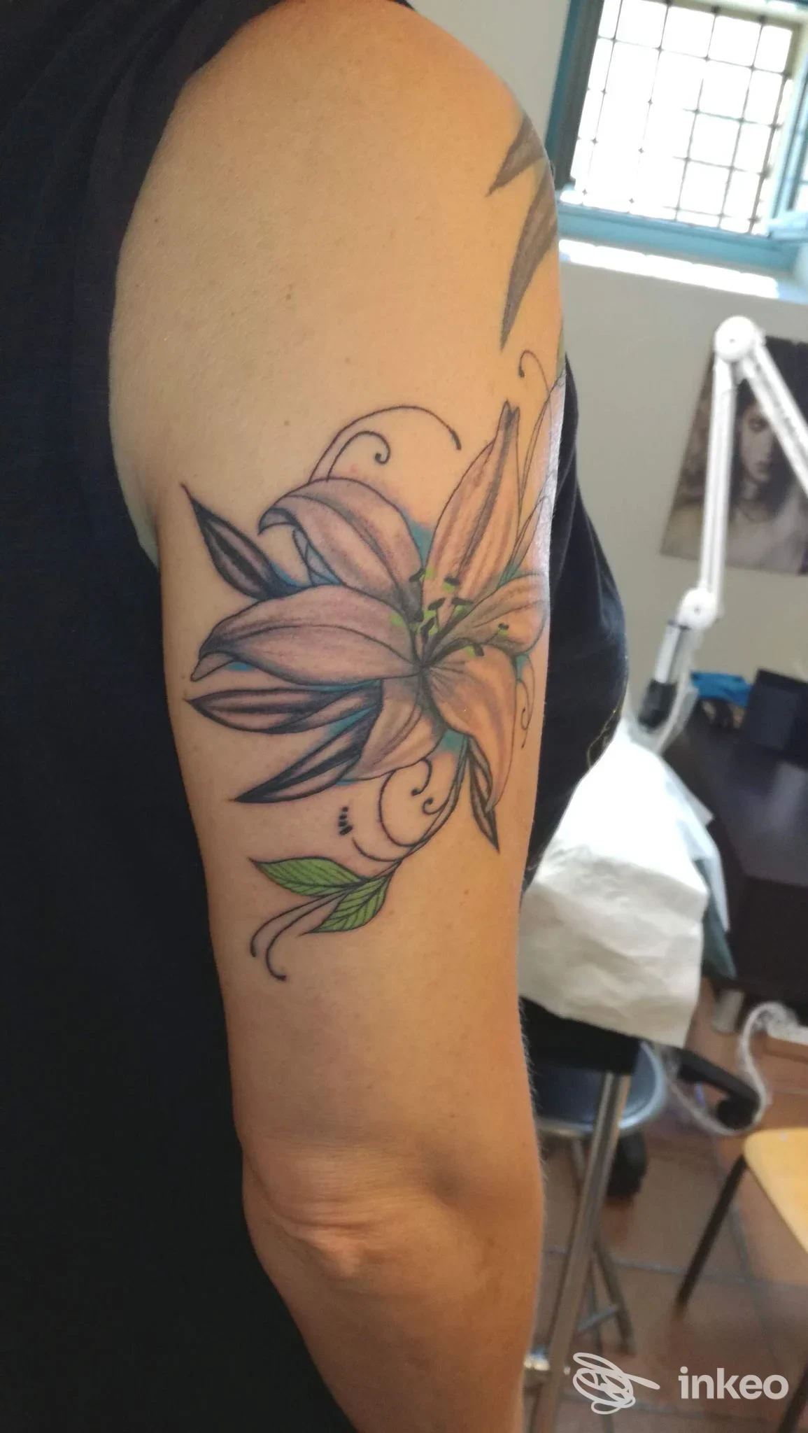Tatuaggio a giglio a colori sul braccio superiore, foto d'interno realizzata presso Tattoo'S Studio di Isabella Caddeo a Foligno.