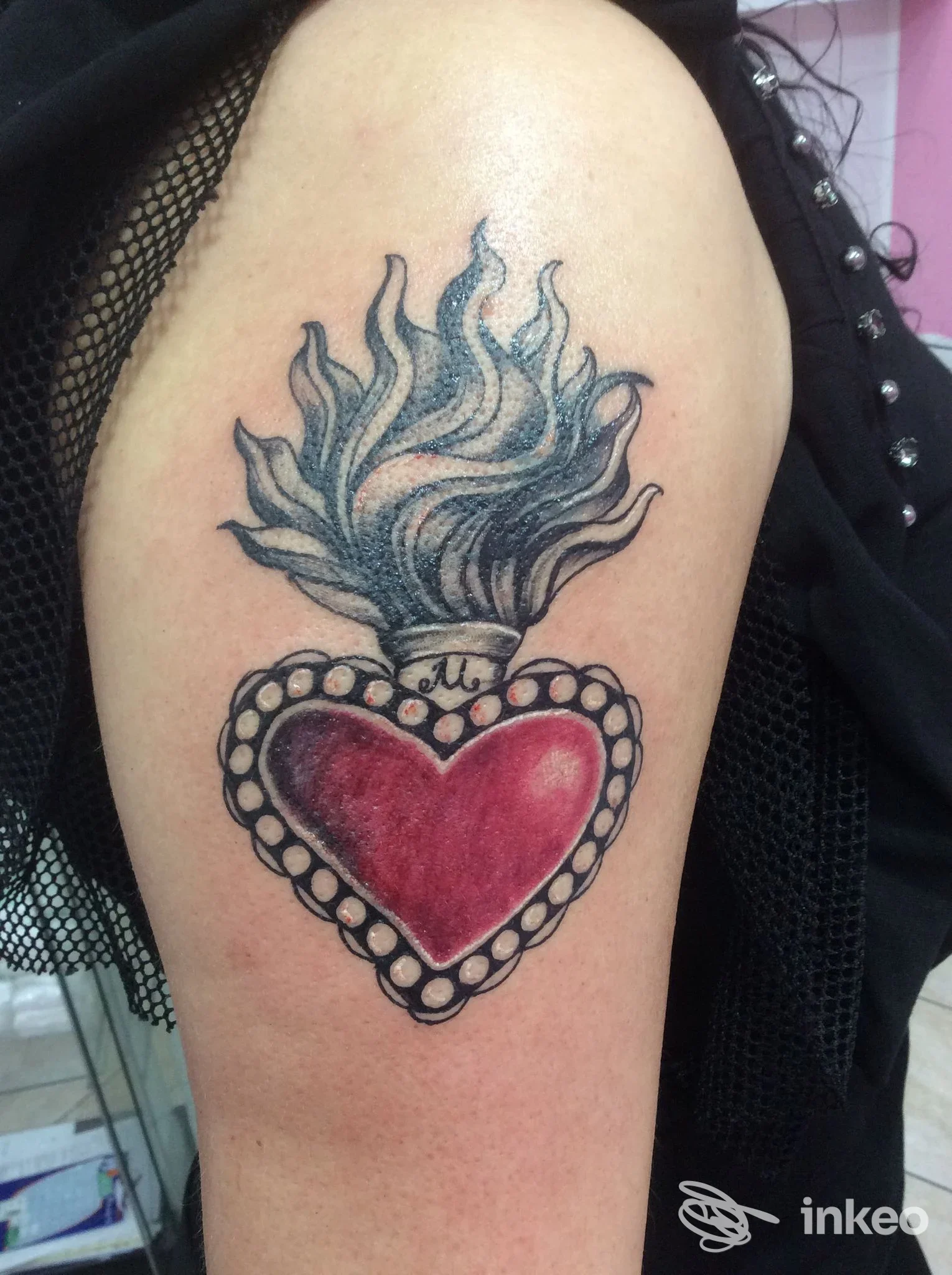 Tatuaggio a forma di cuore fiammeggiante sul braccio superiore, foto fornita da Tattooshka a San Giustino.