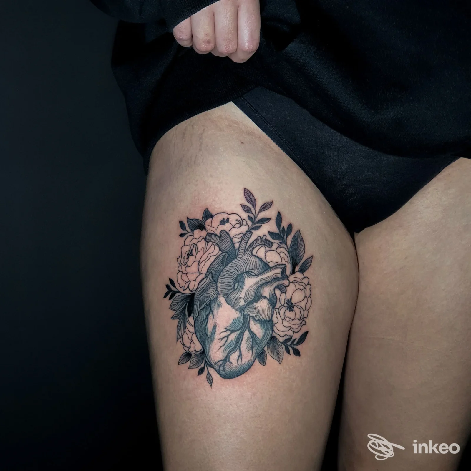 Tatuaggio anatomico sul lato della coscia con cuore e fiori in nero e grigio, immagine inviata da Translab Tattoo e Piercing, Perugia.