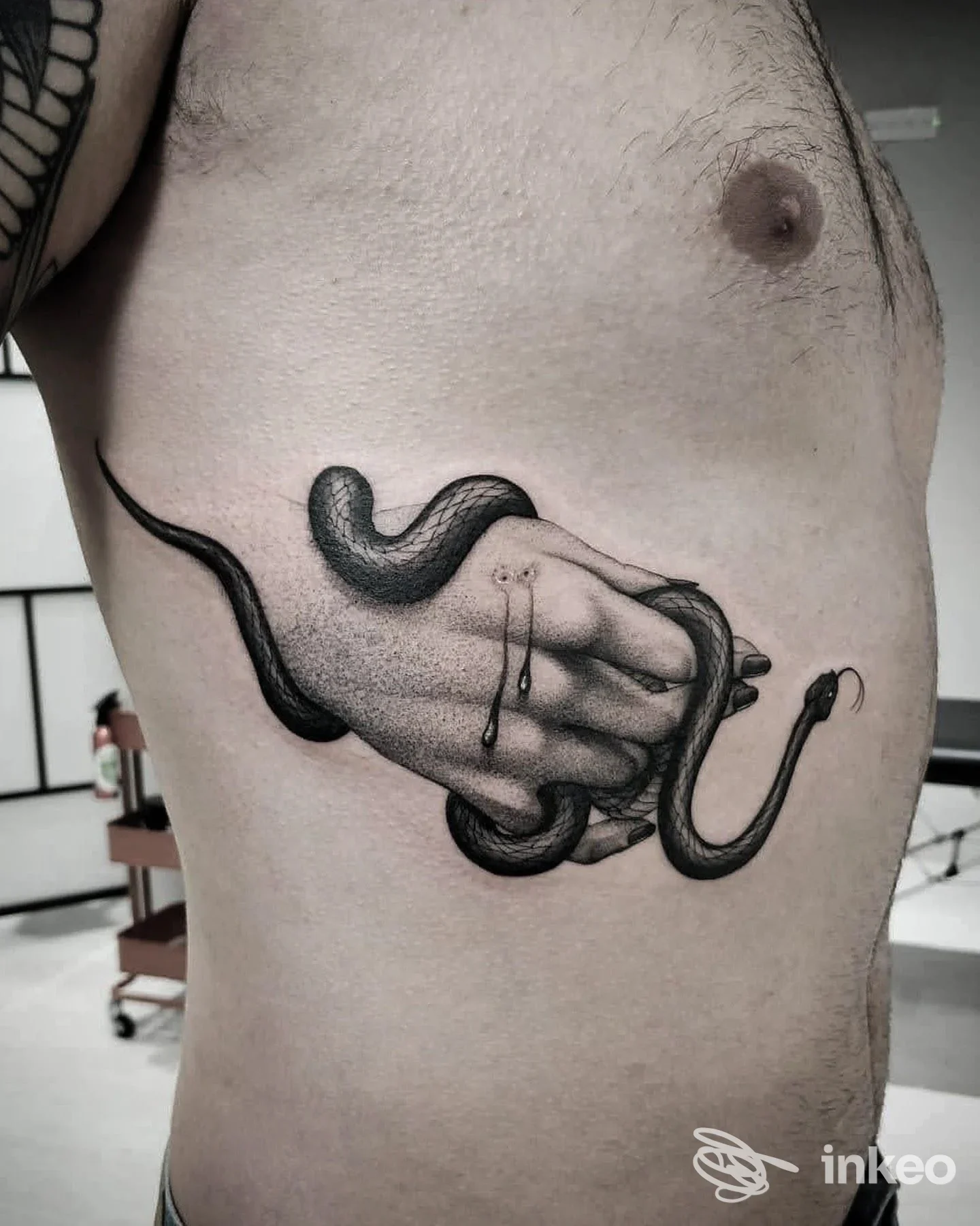 Fotografia del tatuaggio nero sul fianco: mano avvolta da un serpente, scatto presso Wizard Tattoo, Todi.