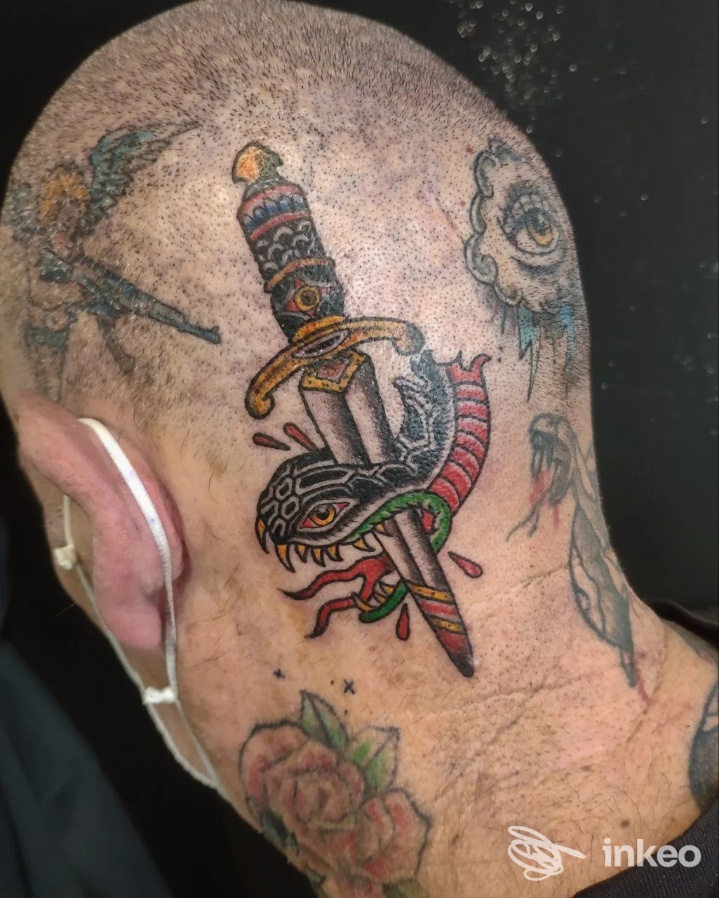 Tatuaggi colorati su testa rasata e collo: pugnale che trafigge un serpente e rose, immagine fornita da simoncino88 Tattoo, Spoleto.