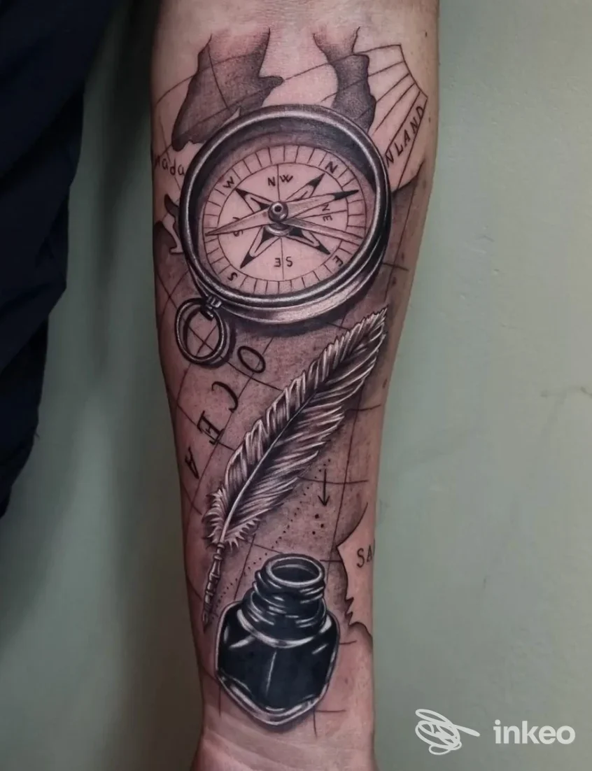 Tatuaggio su avambraccio con bussola, piuma e calamaio, eseguito da 4810 Mountainink Tattoo Studio - Sarre.