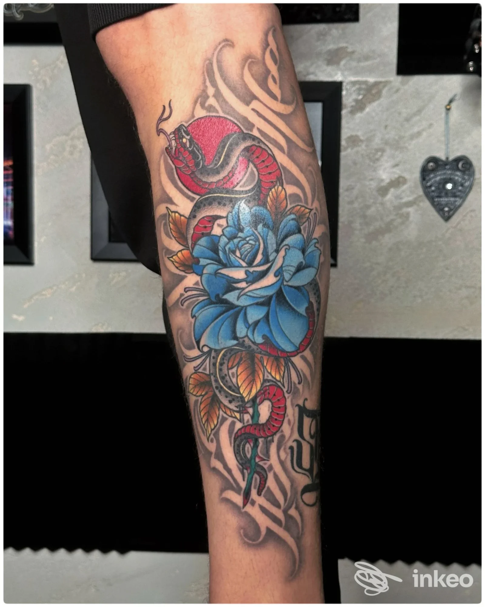 Avambraccio tatuato con grande fiore blu e serpente rosso, foto fornita da Jack Puma Tattoo Studio, Aosta.