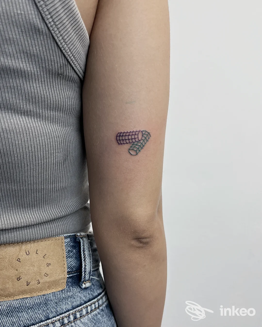 Piccolo tatuaggio geometrico colorato sul braccio superiore esterno, fotografato per 37049 TattooStudio, Villa Bartolomea.