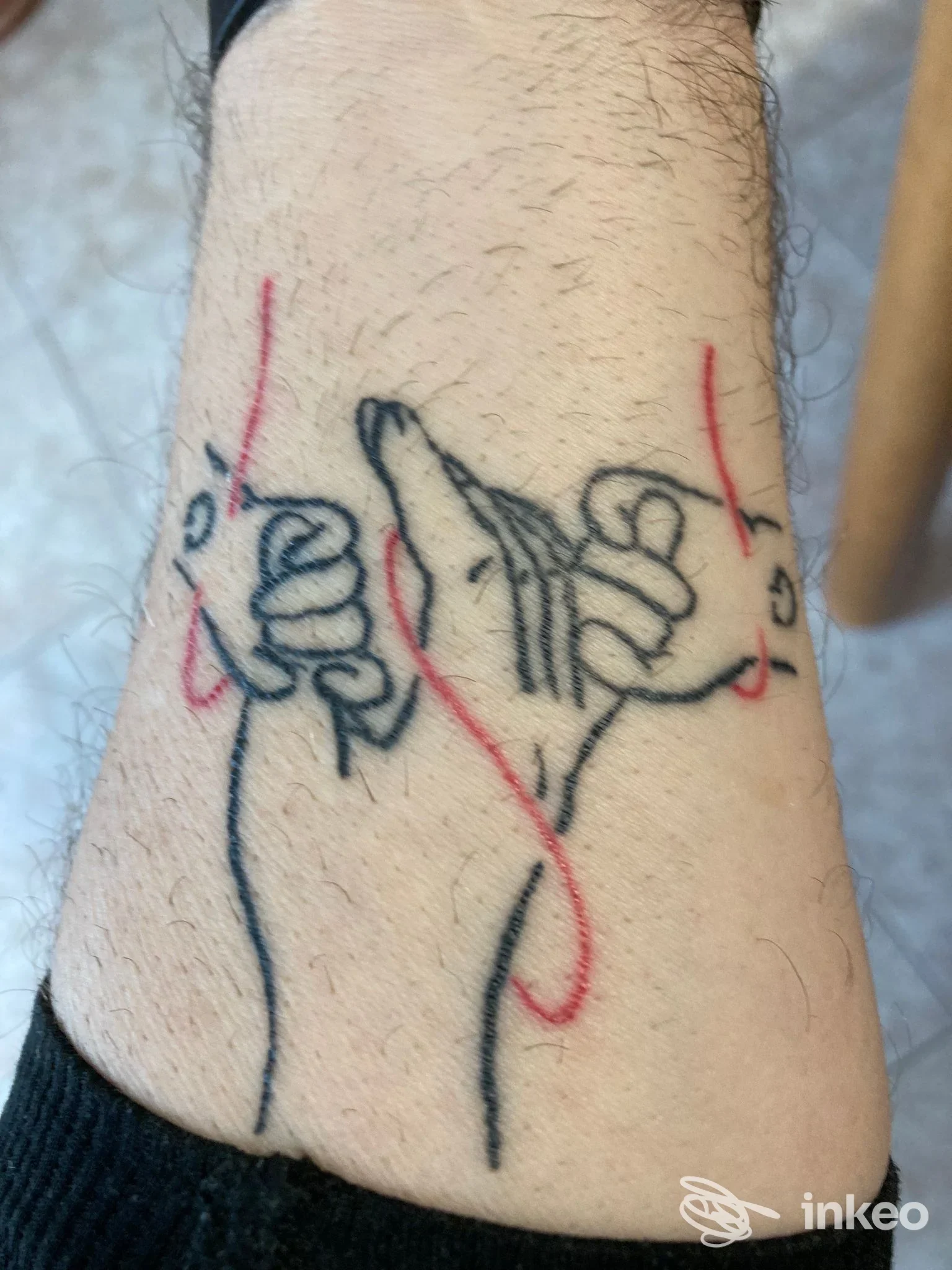 Tatuaggio a linee di due mani con filo rosso sull'avambraccio, foto inviata da Aisha Tattoo & piercing a Thiene.