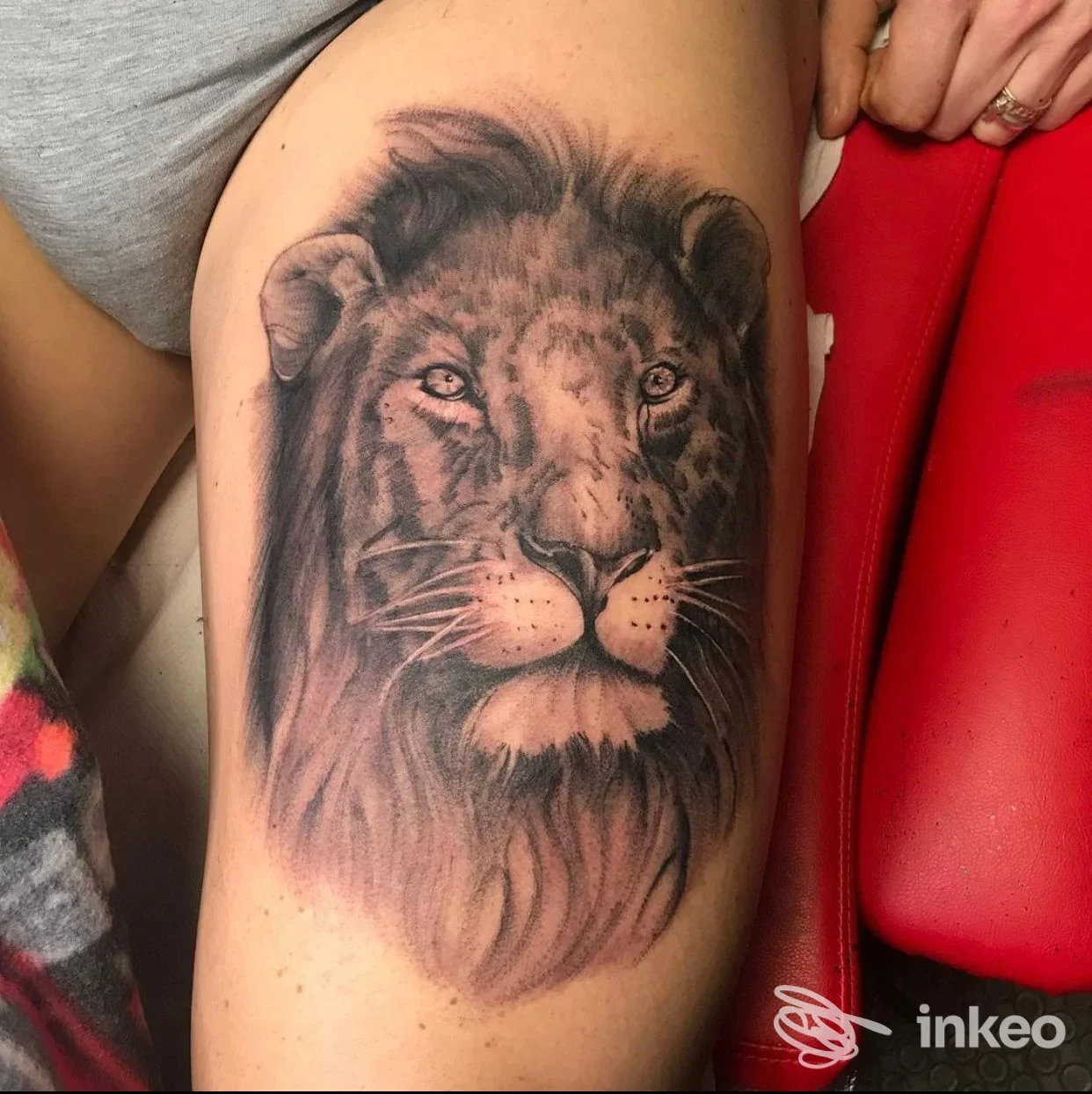 Tatuaggio realistico in bianco e nero di una testa di leone sulla coscia, eseguito da Alchimista tattoo-piercing a Cazzago.