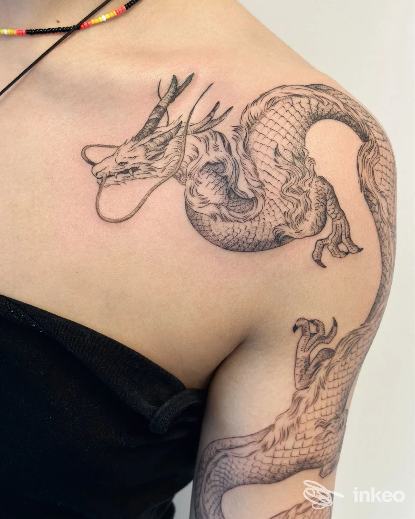 Tatuaggio di drago a linee sottili su spalla e parte superiore del braccio, foto per Artium Tattoo Emporium a Montebelluna.