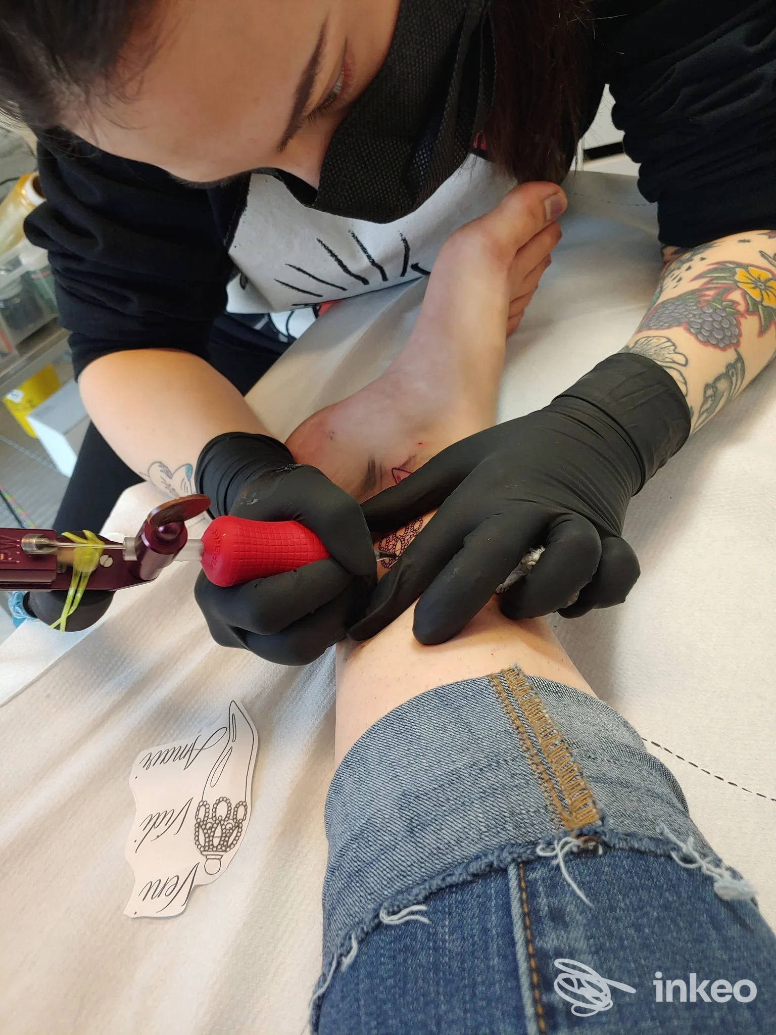 Operatrice tatuatrice al lavoro sulla caviglia di un cliente nello studio BIKINI BOTTOM TATTOO STUDIO, Vicenza.