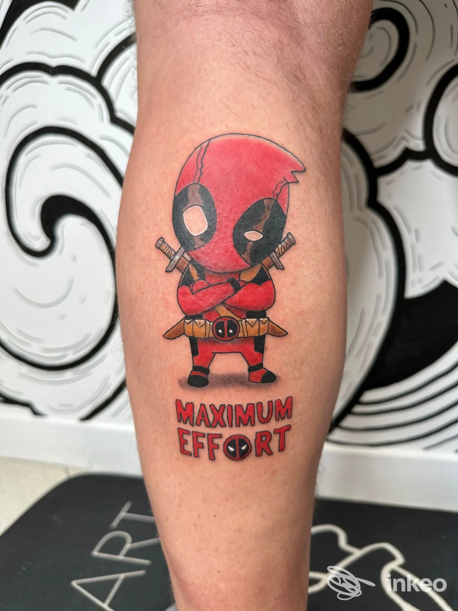 Tatuaggio Deadpool colorato sul polpaccio con scritta 'MAXIMUM EFFORT', fotografato nello studio B_heART Tattoo Shop a Farra D'Alpago.