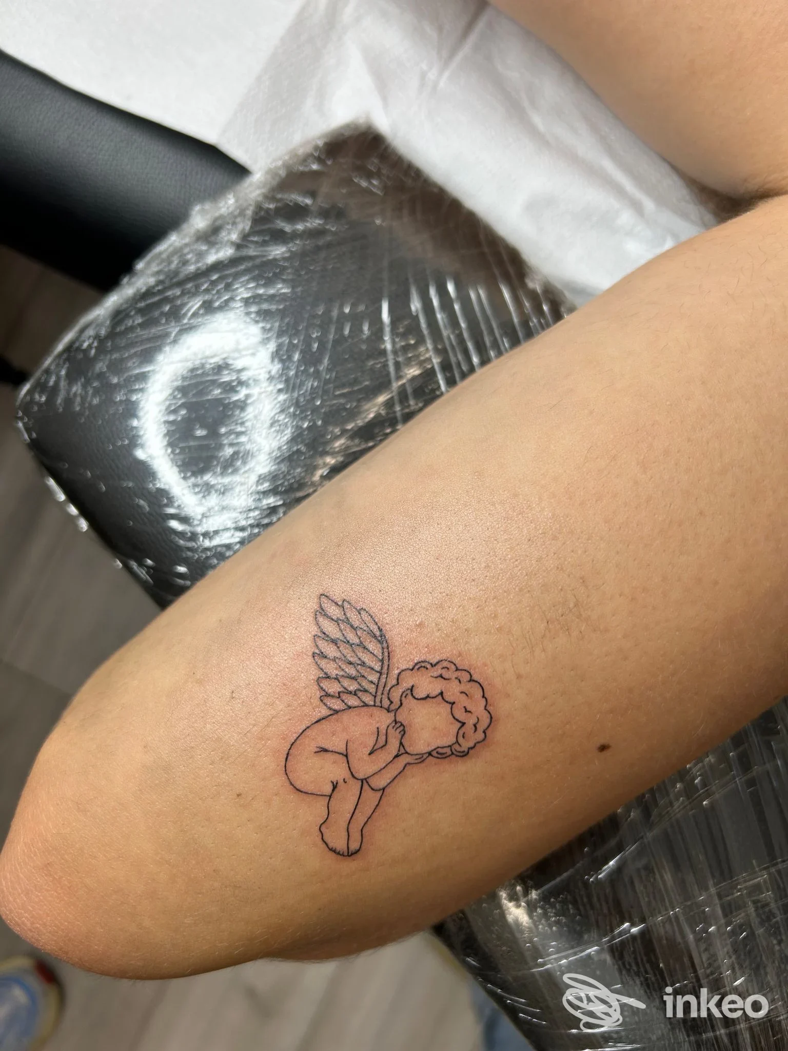 Piccolo tatuaggio linework a forma di angelo sull'interno del gomito, foto scattata da Bandit Tattoo Studio, Padova.
