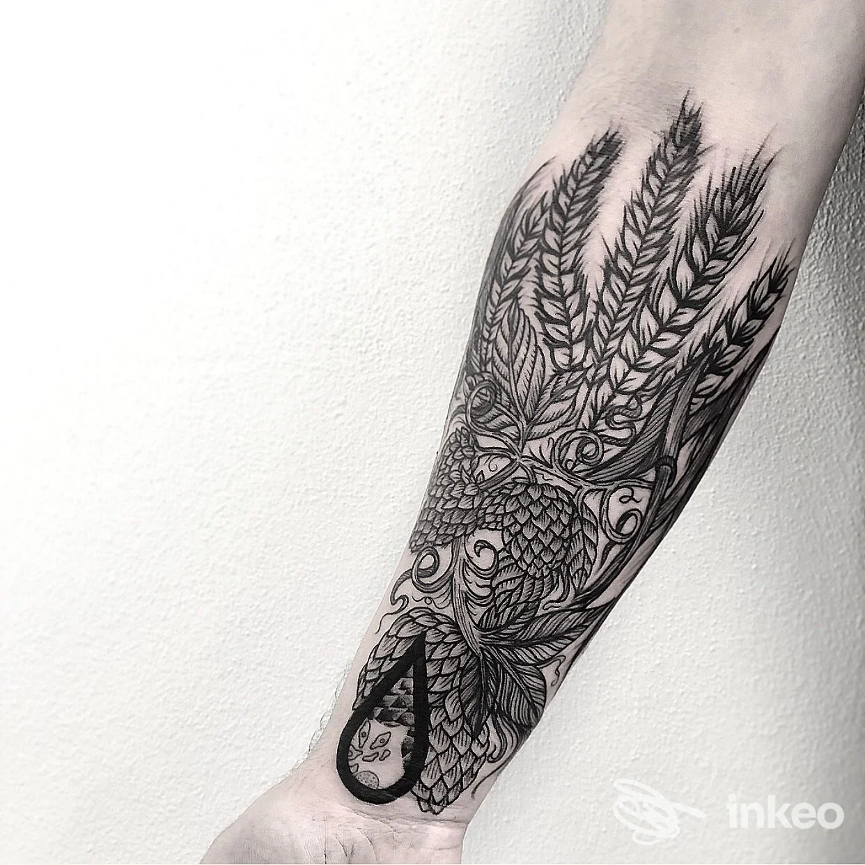Tatuaggio nero sull'avambraccio con gufo stilizzato e spighe, foto fornita da Alex De Pase Stores Tattoo e Piercing, Venezia.