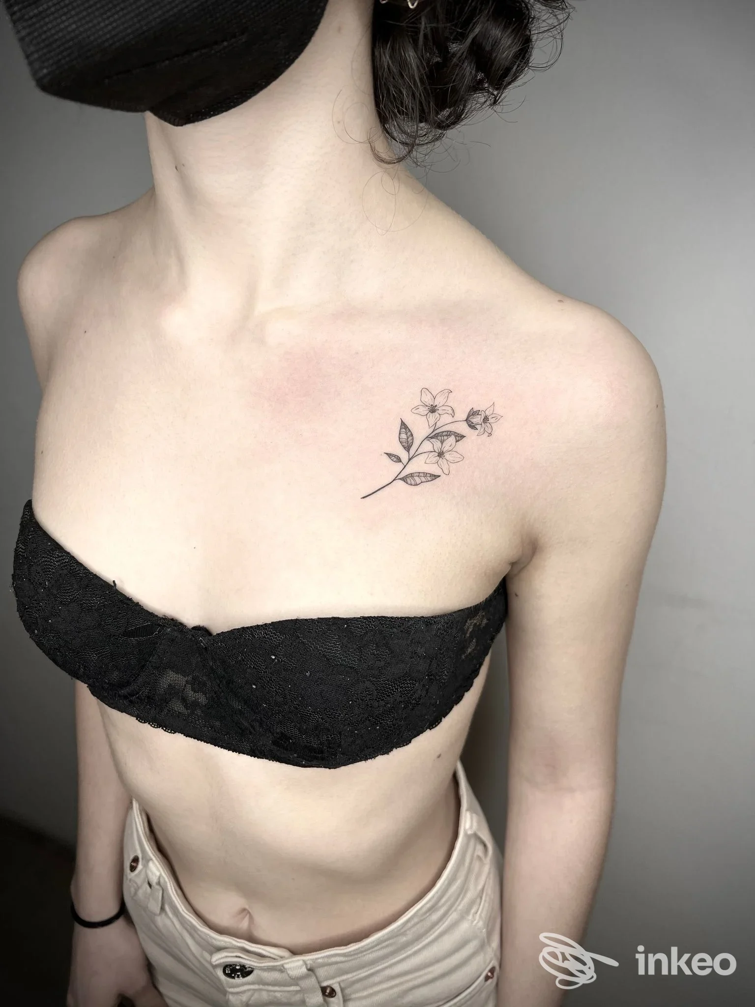 Tatuaggio floreale a linee sottili sul pettorale superiore vicino alla clavicola, fotografato in studio Blaack ink tattoo studio a Vicenza.