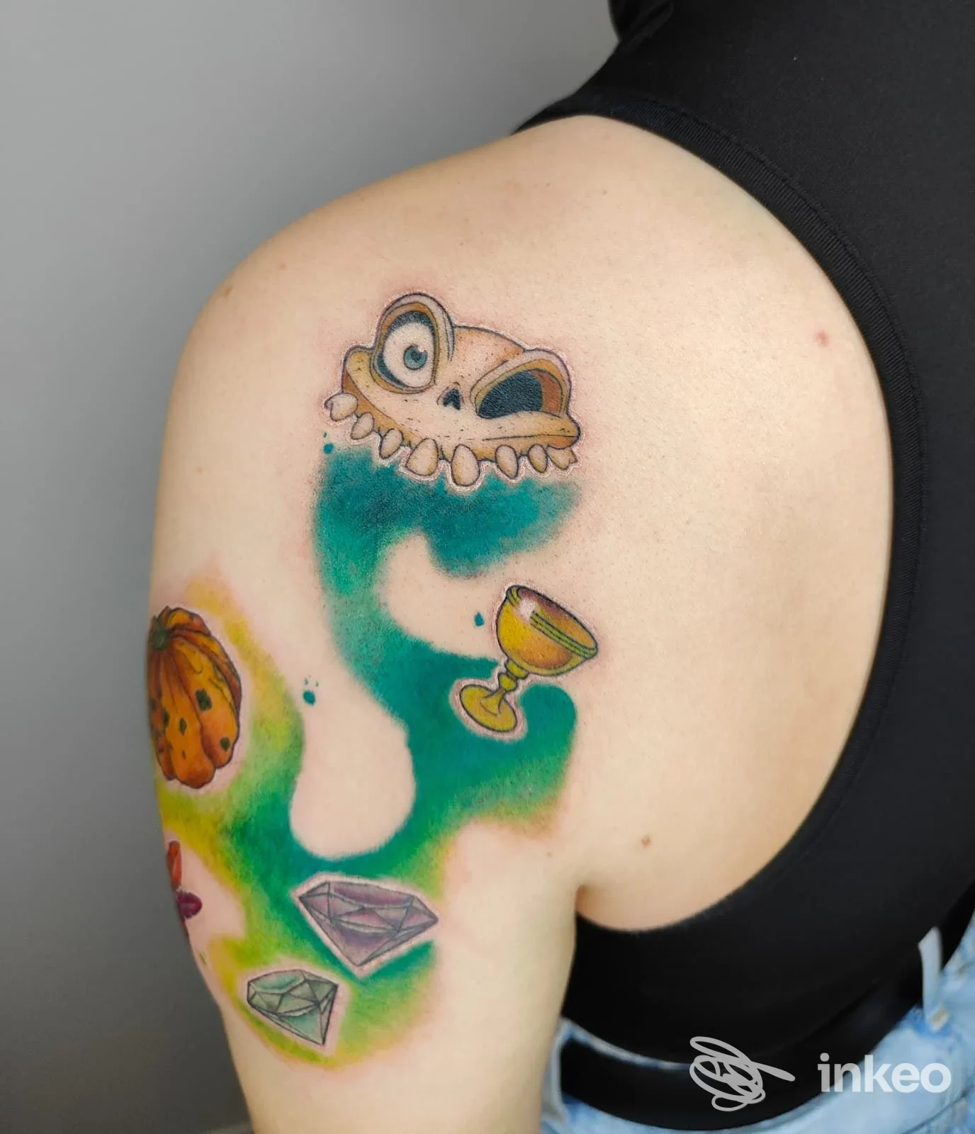 Tatuaggio colorato su spalla con elementi illustrativi (cranio stilizzato, calice, gemme) — Black Diamond Tattoo, Gorgo al Monticano.