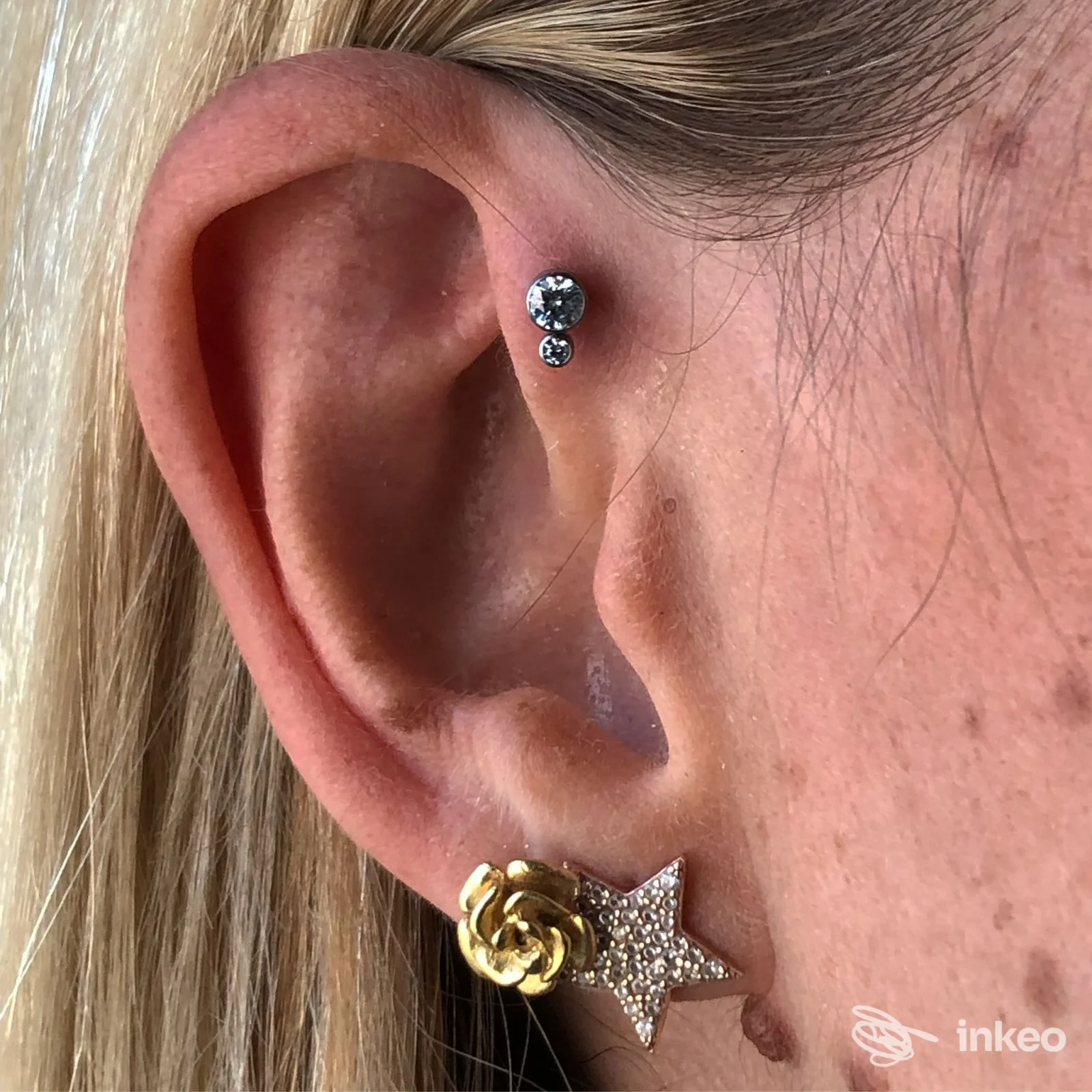 Primo piano di un orecchio con piercing alla conchiglia e al lobo, gioielli brillanti; immagine fornita da Body Piercing Lara, Verona.
