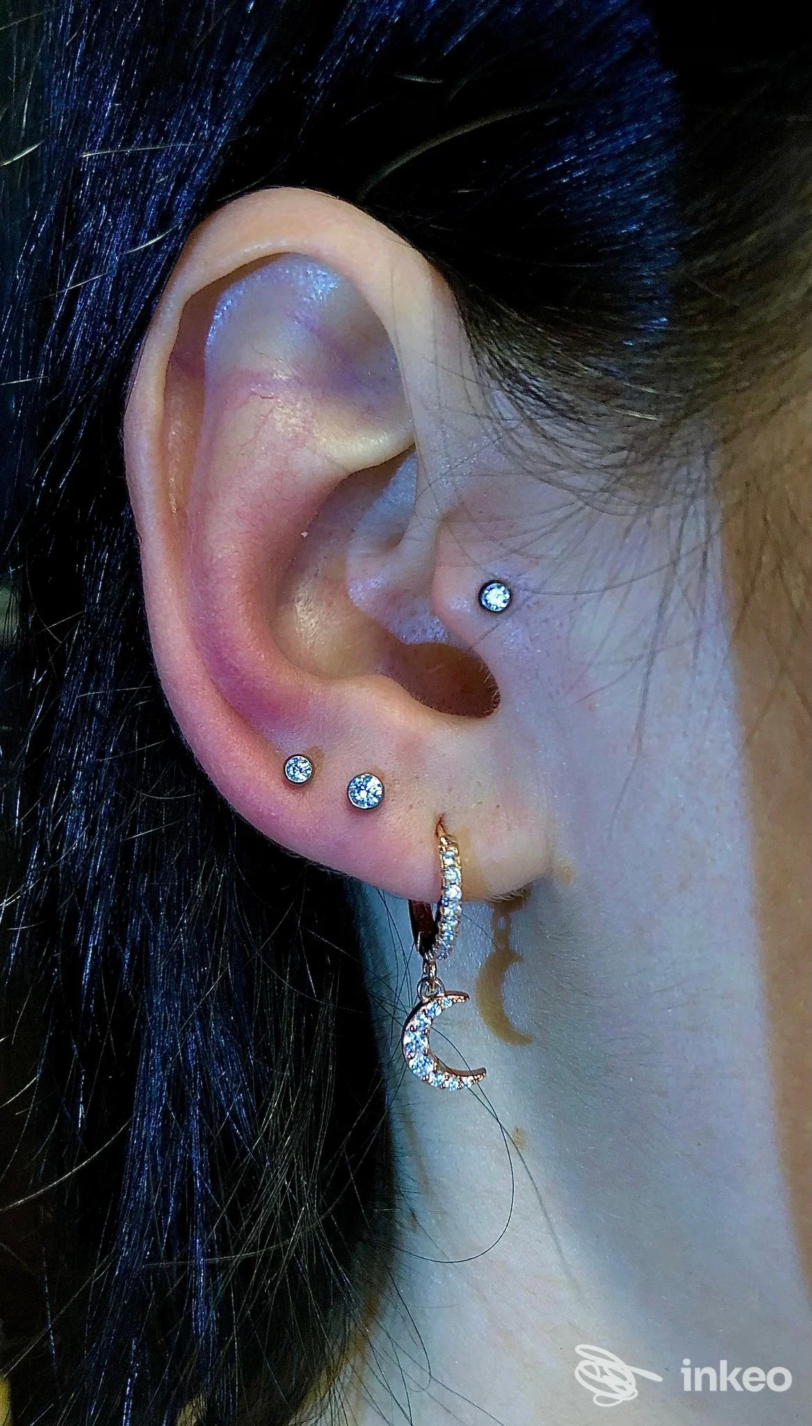 Primo piano di orecchio con più piercing e un orecchino pendente, Body Piercing Lara, Verona.