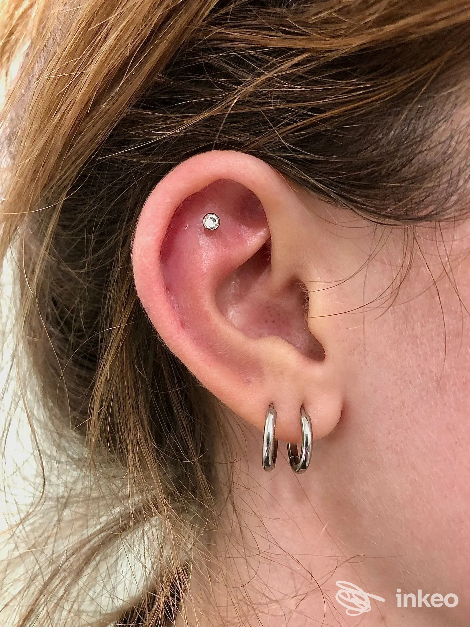 Primo piano di orecchio con piercing alla conchiglia e due anellini al lobo, foto di Body Piercing Lara, Verona.