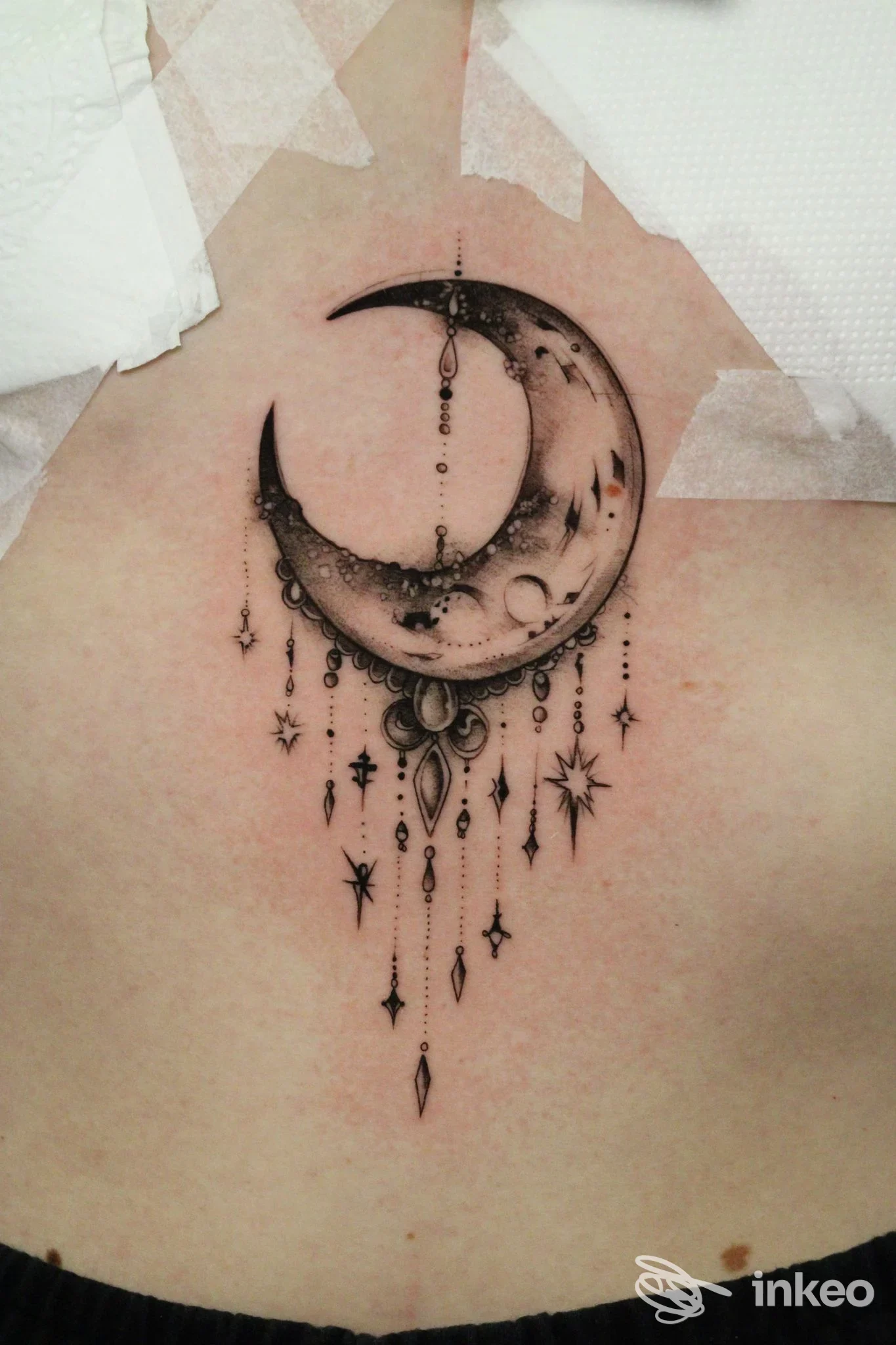 Tatuaggio a mezzaluna nera con pendenti ornamentali sulla parte alta della schiena, foto fornita da BOG Tattoo a Santa Giustina in Colle.