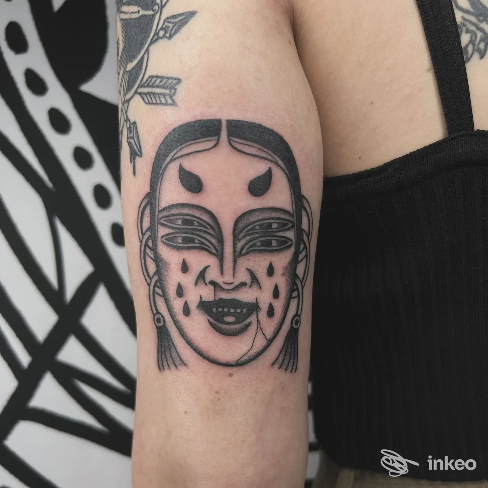 Tatuaggio blackwork a volto stilizzato sull'esterno del braccio, fotografia fornita da Bubka Tattoo Shop a Cassola.