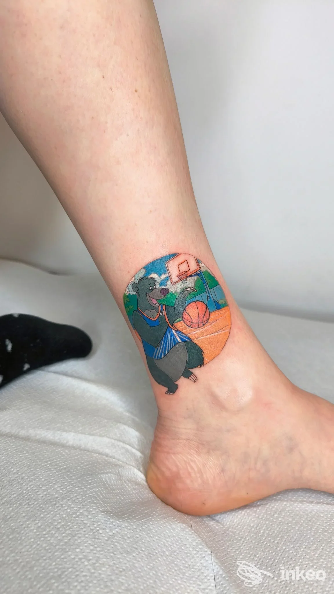 Tatuaggio colorato alla caviglia raffigurante un orso che gioca a basket, realizzato da Caterina tattoo a Codiverno.