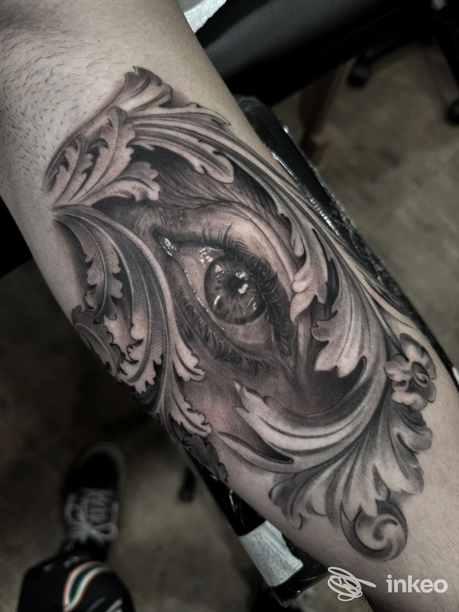 Tatuaggio realistico di un occhio incorniciato da ornamenti floreali sull'avambraccio. Cerbero family Tattoo Studio, Treviso.