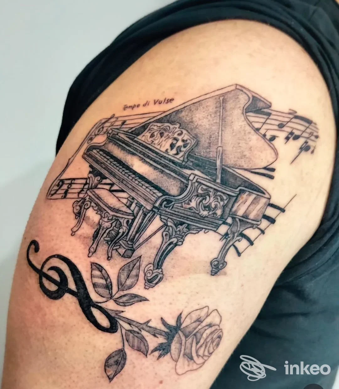 Tatuaggio sul bicipite con pianoforte a coda, spartito, chiave di violino e rosa. Cesar Tattoo Studio, Piovene Rocchette.