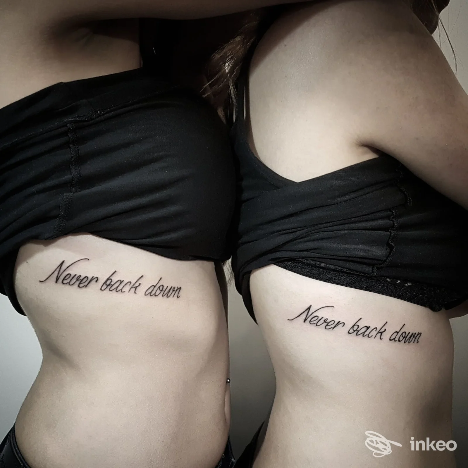 Due tatuaggi testuali 'Never back down' sui fianchi di due persone, fotografia realizzata per DEMON - Piercing & Tattoo, Verona.